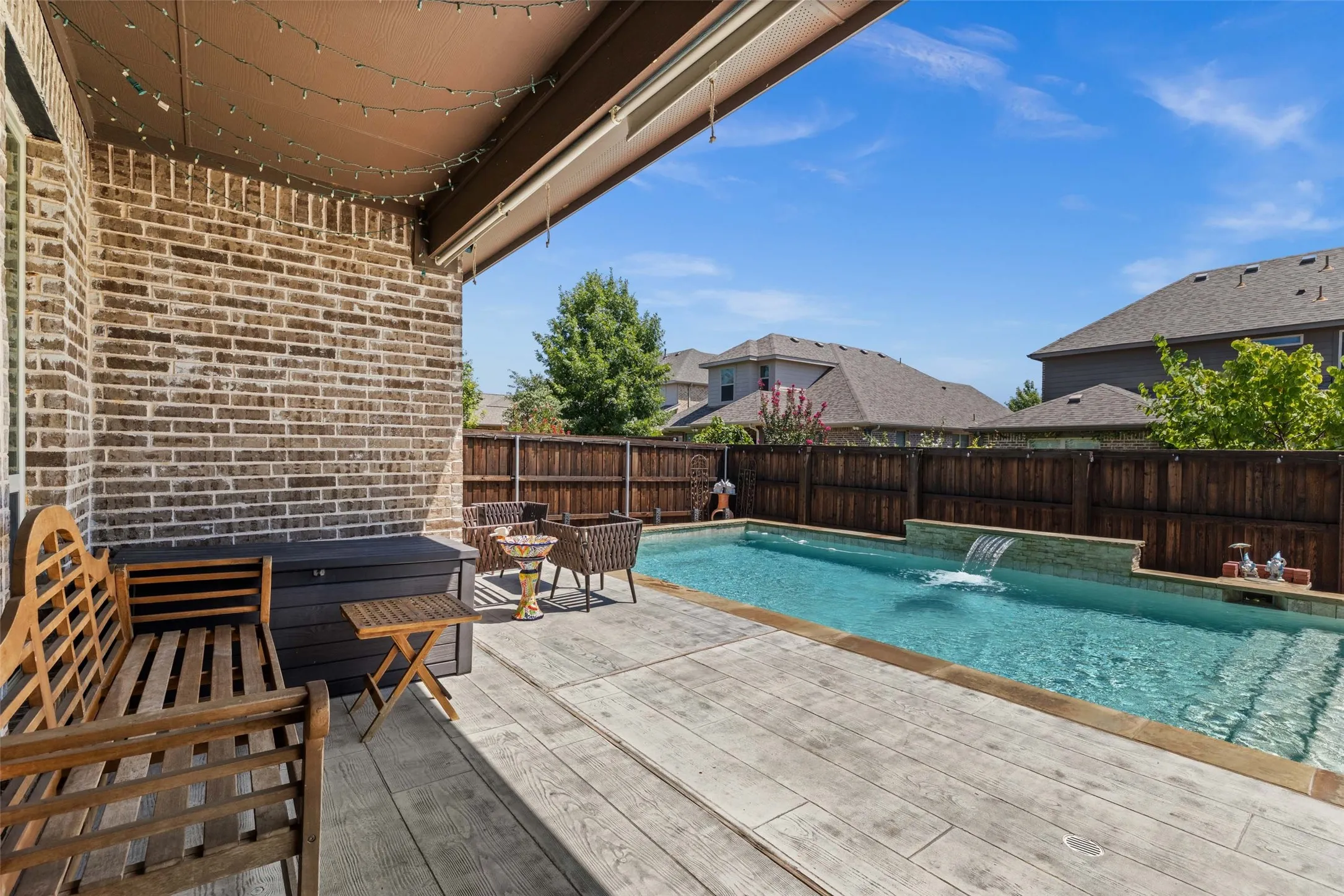 Outdoor covered patio with brick wall and concrete-stamped flooring