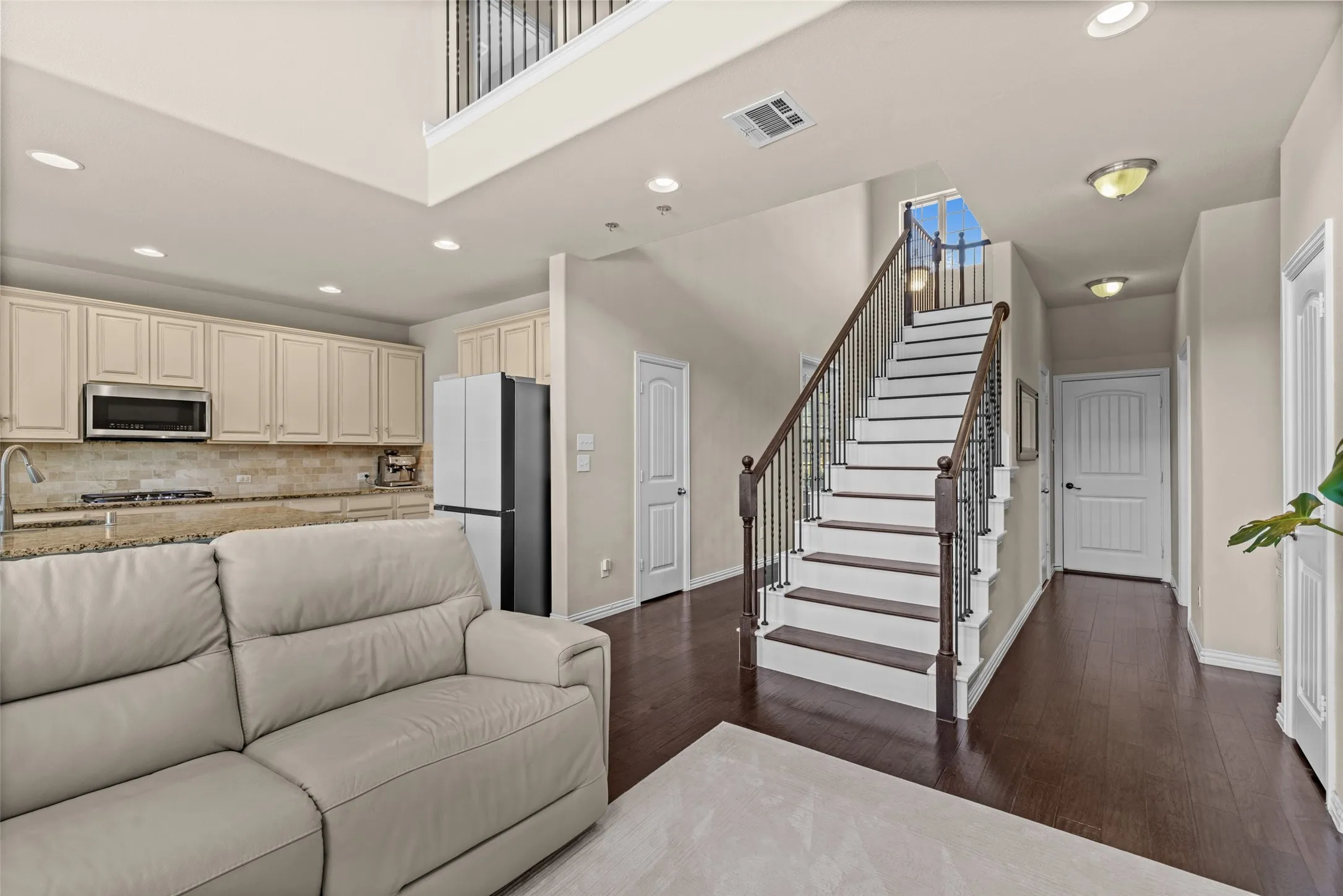 Open-concept living area with dark wood-finish flooring, recessed lighting, and a two-story ceiling