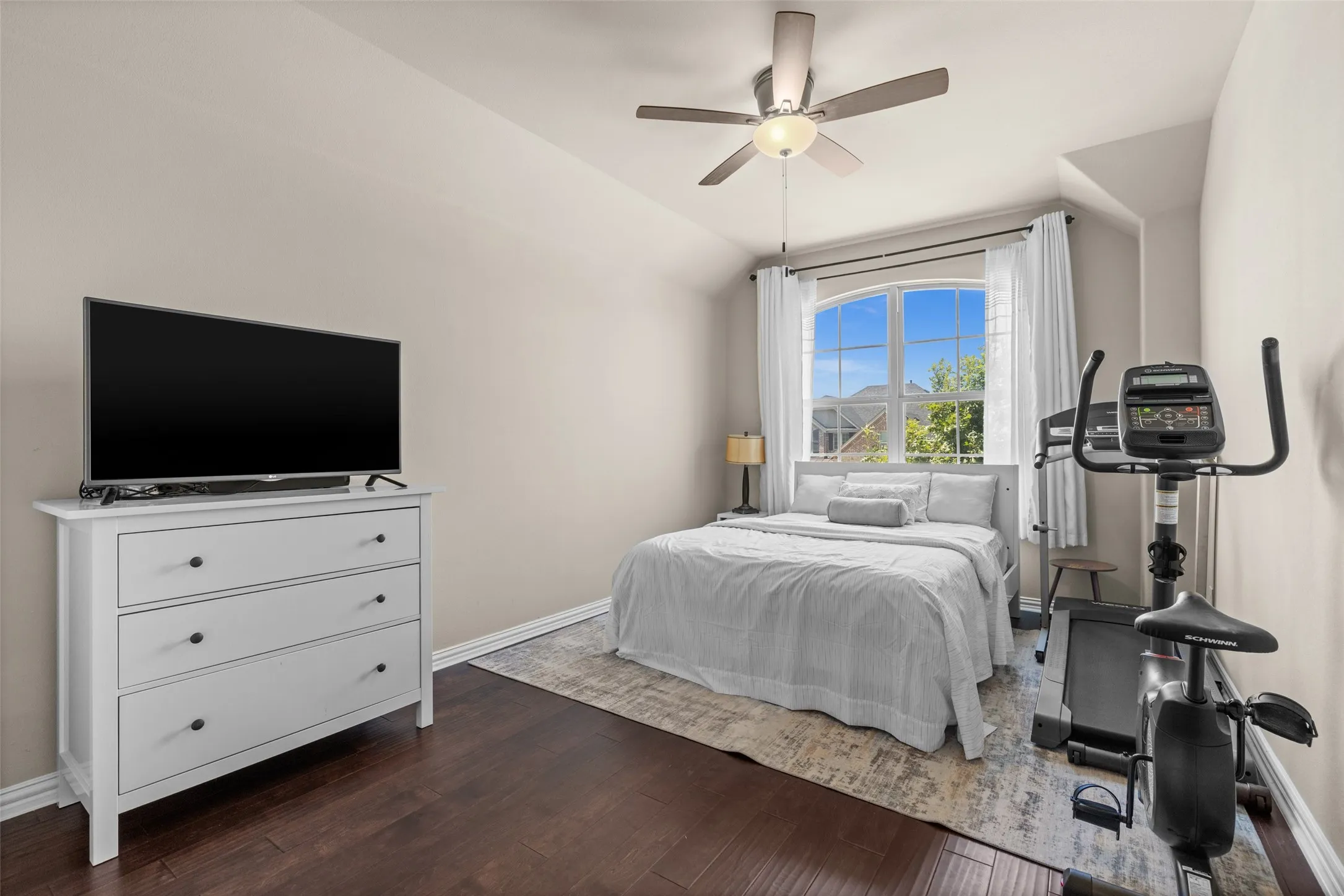 Arch-top window with white trim, dark wood-finish flooring, and a ceiling fan with integrated lighting