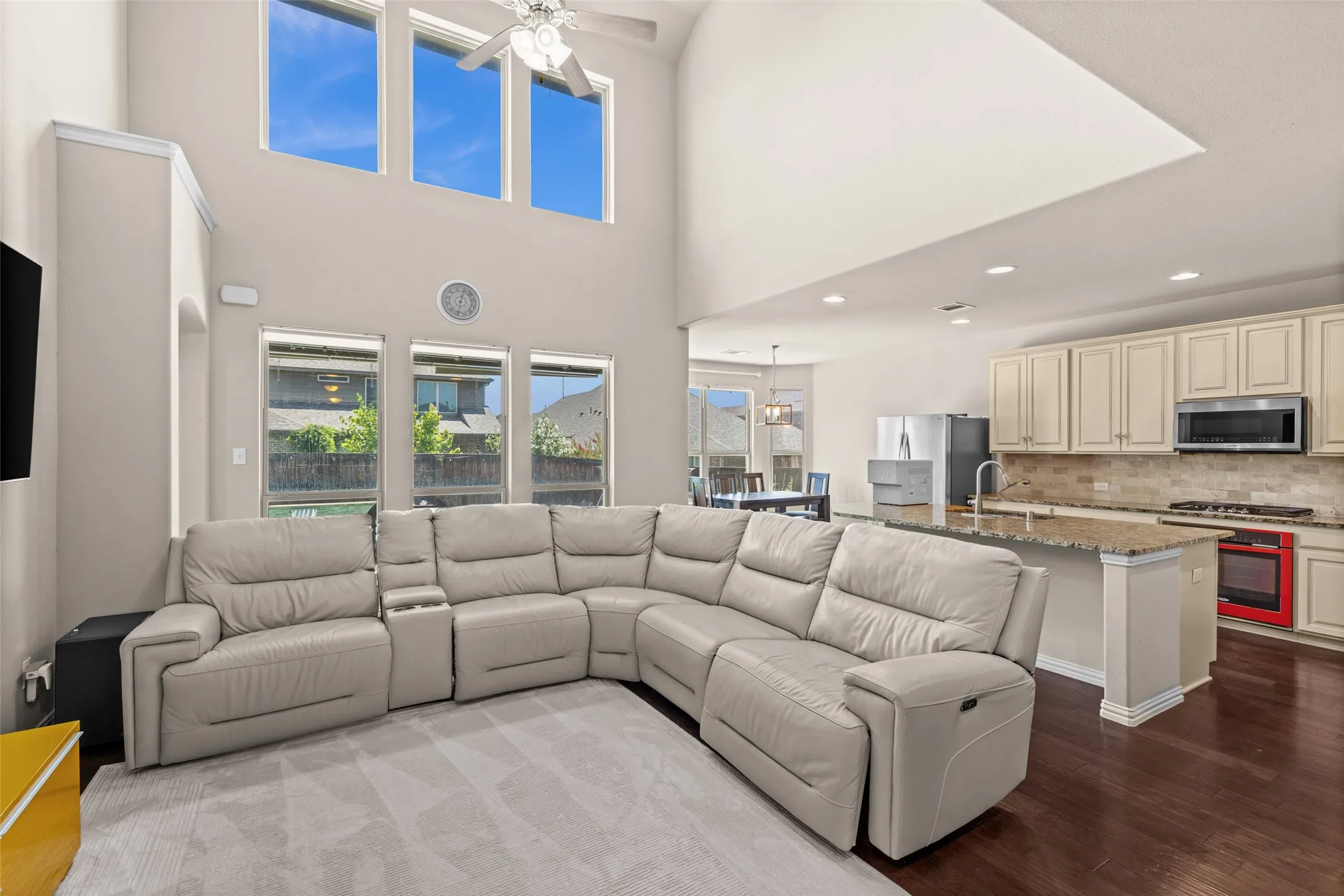 Vaulted ceiling with a ceiling fan, three upper transom windows, recessed lighting, and dark wood-finish flooring