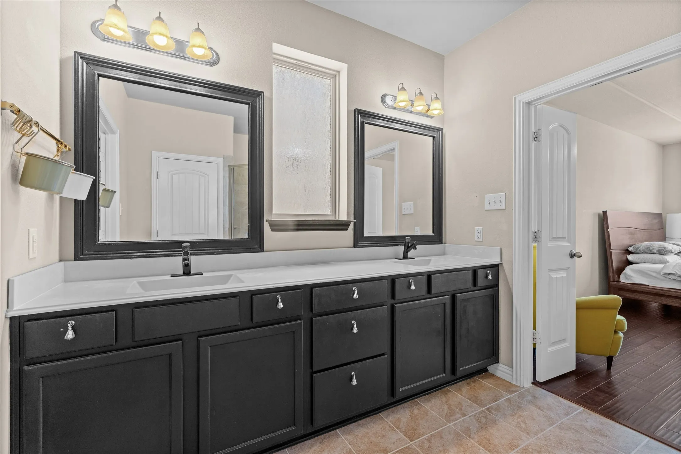 Dual vanities featuring dark cabinetry, white countertops, undermount sinks, and wall-mounted light fixtures
