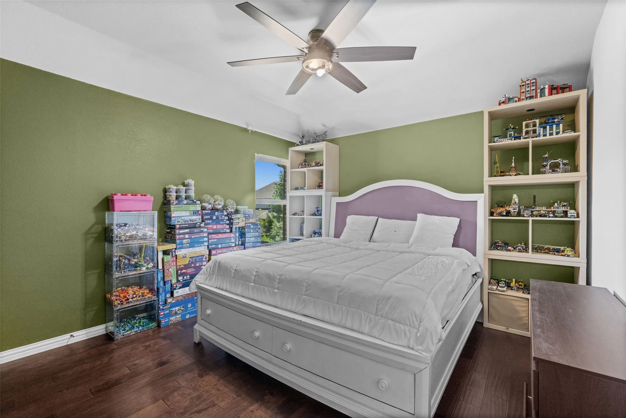 Wood-finish flooring, ceiling fan, built-in shelving, window with exterior view, and painted accent walls