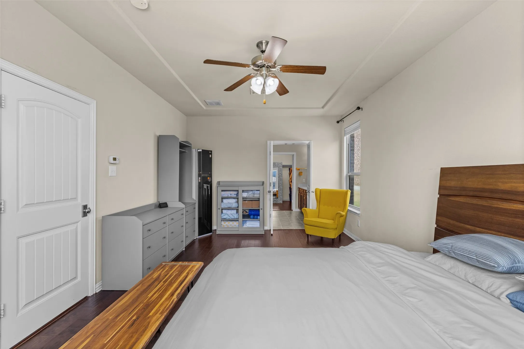 Tray ceiling with ceiling fan, wood-finish flooring, and a white paneled door