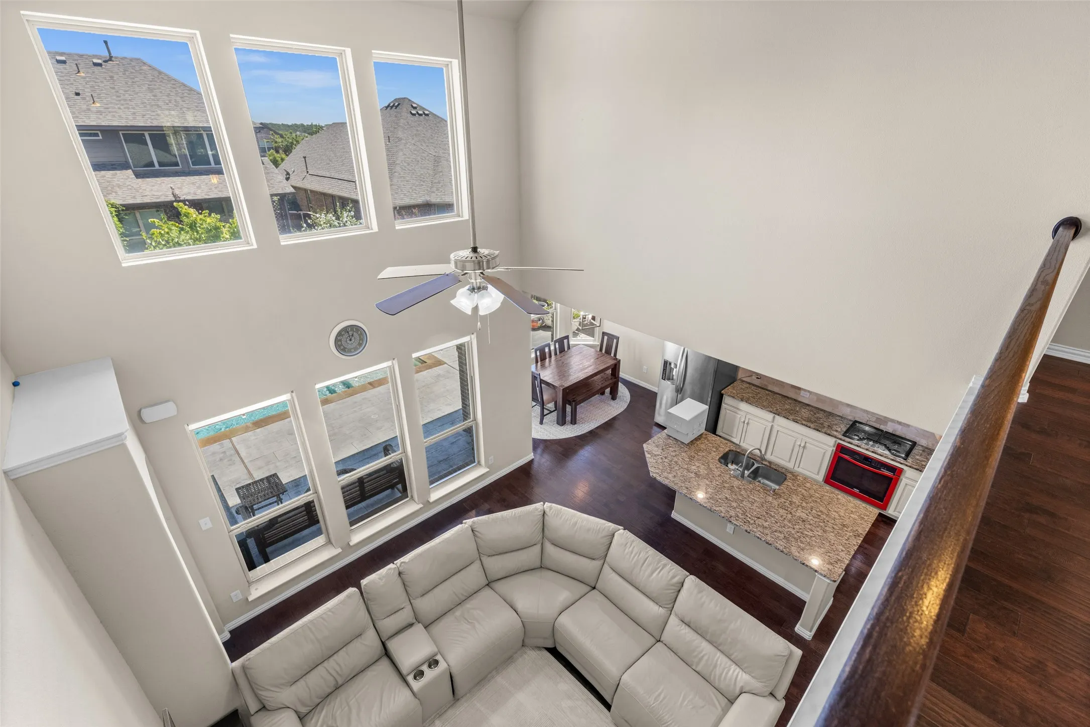 Soaring ceilings with upper-level windows, wood-finish flooring, and a kitchen featuring a center island with sink