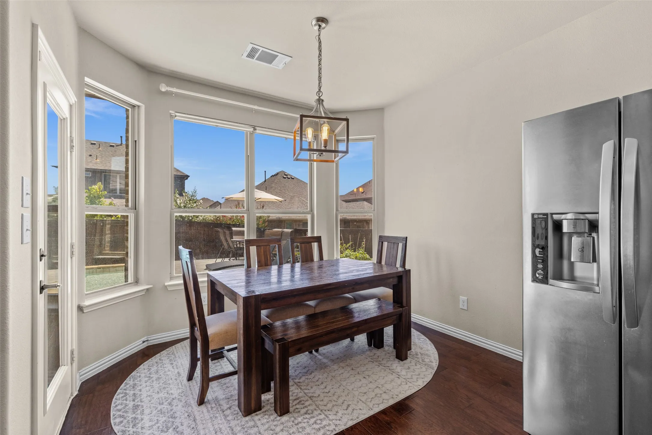 Dining area with dark wood-finish flooring, white walls, and a contemporary chandelier