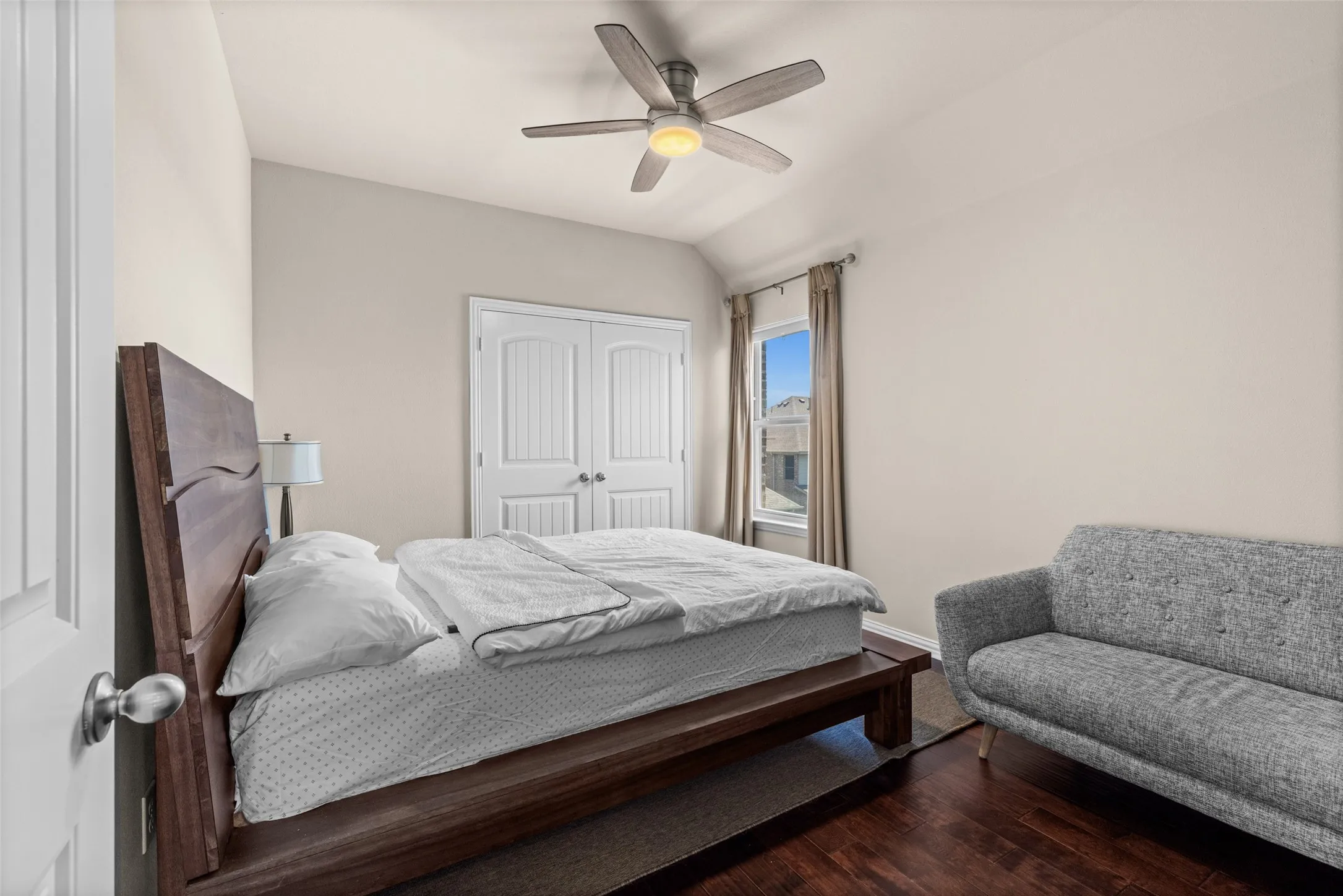 Vaulted ceiling with a ceiling fan, recessed window, two-panel interior doors, and wood-finish flooring