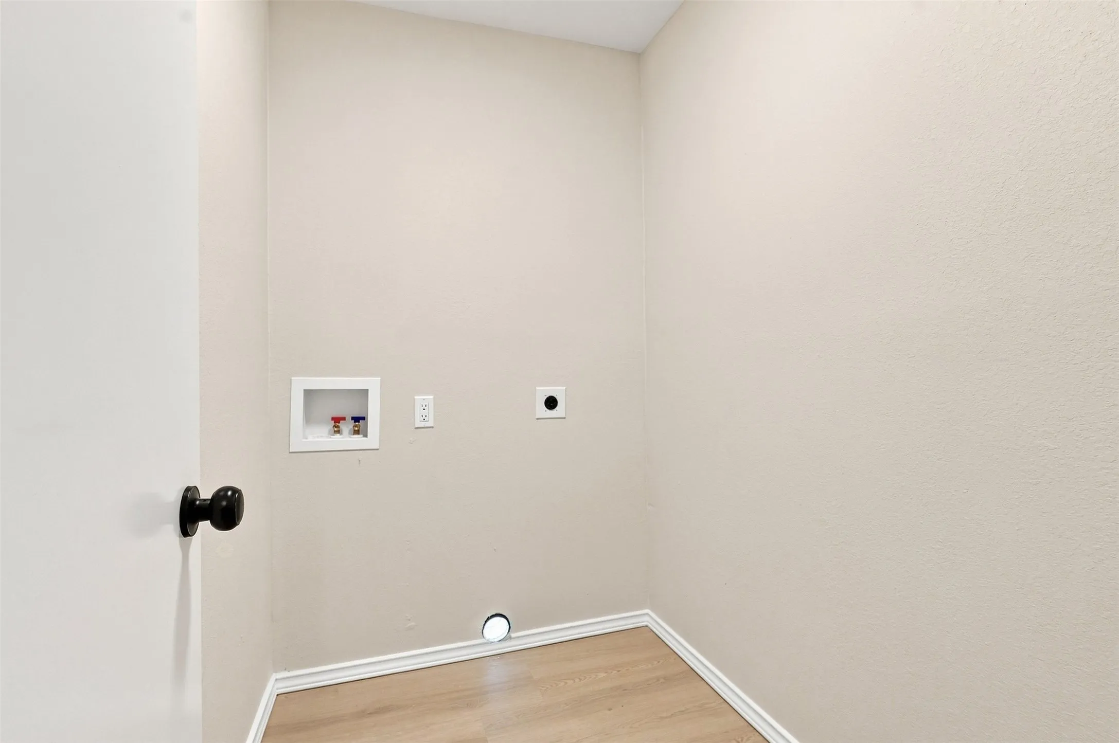 Utility connections for laundry appliances, wood-finish flooring, and light-toned walls