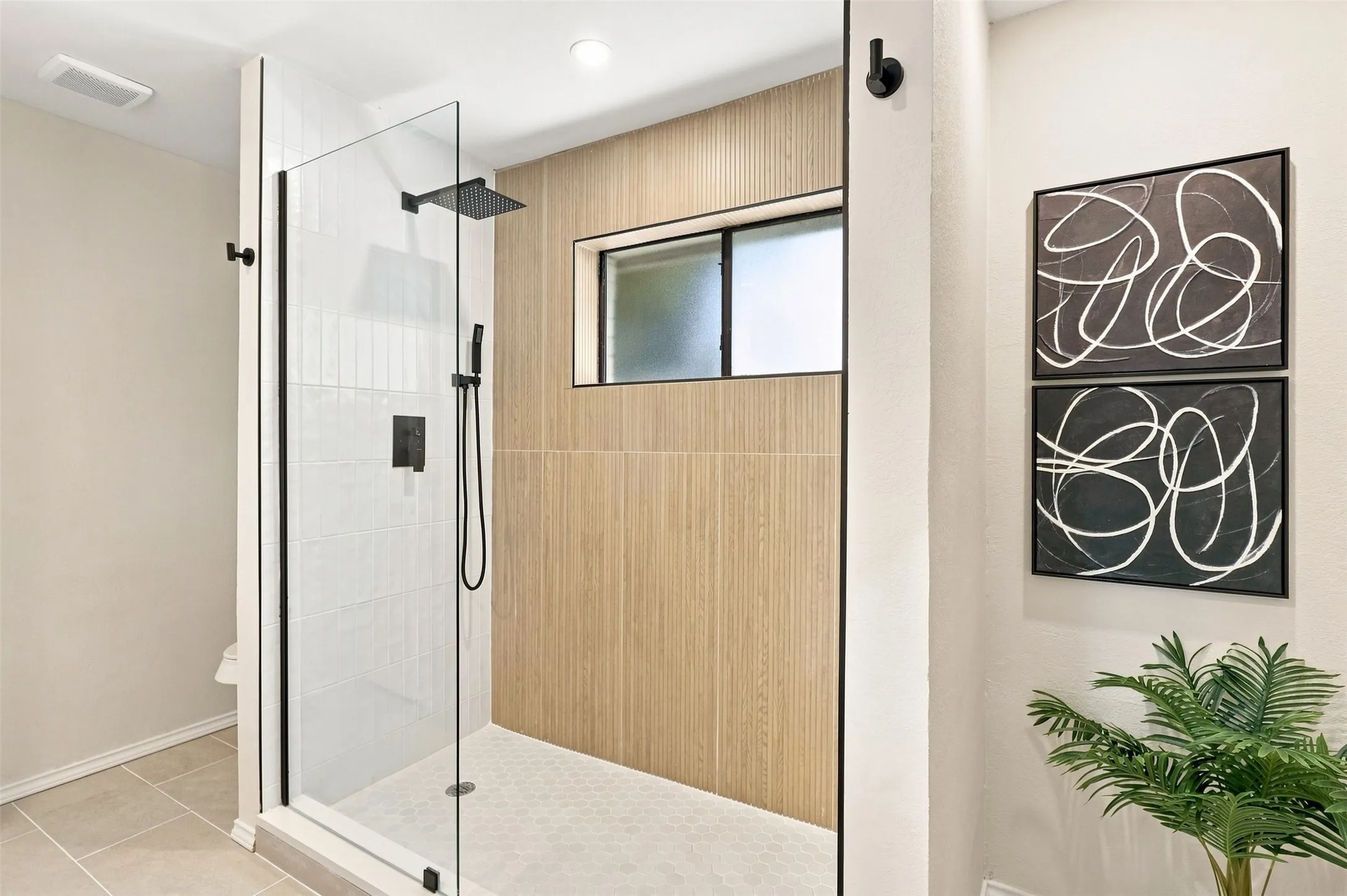 Glass-enclosed shower with matte black fixtures, rain shower head, and an integrated shower wand