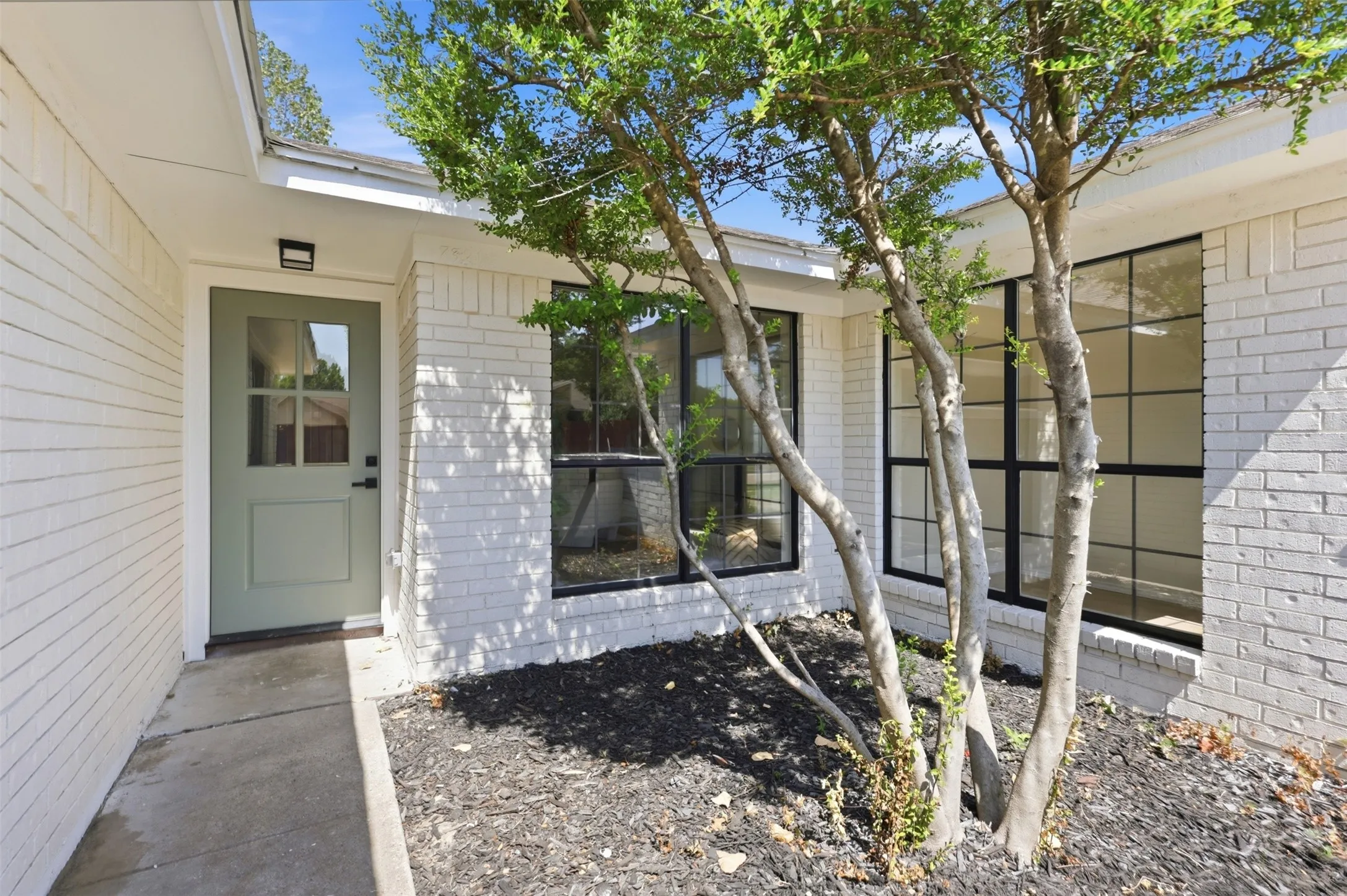 White painted brick exterior with a sage green front door