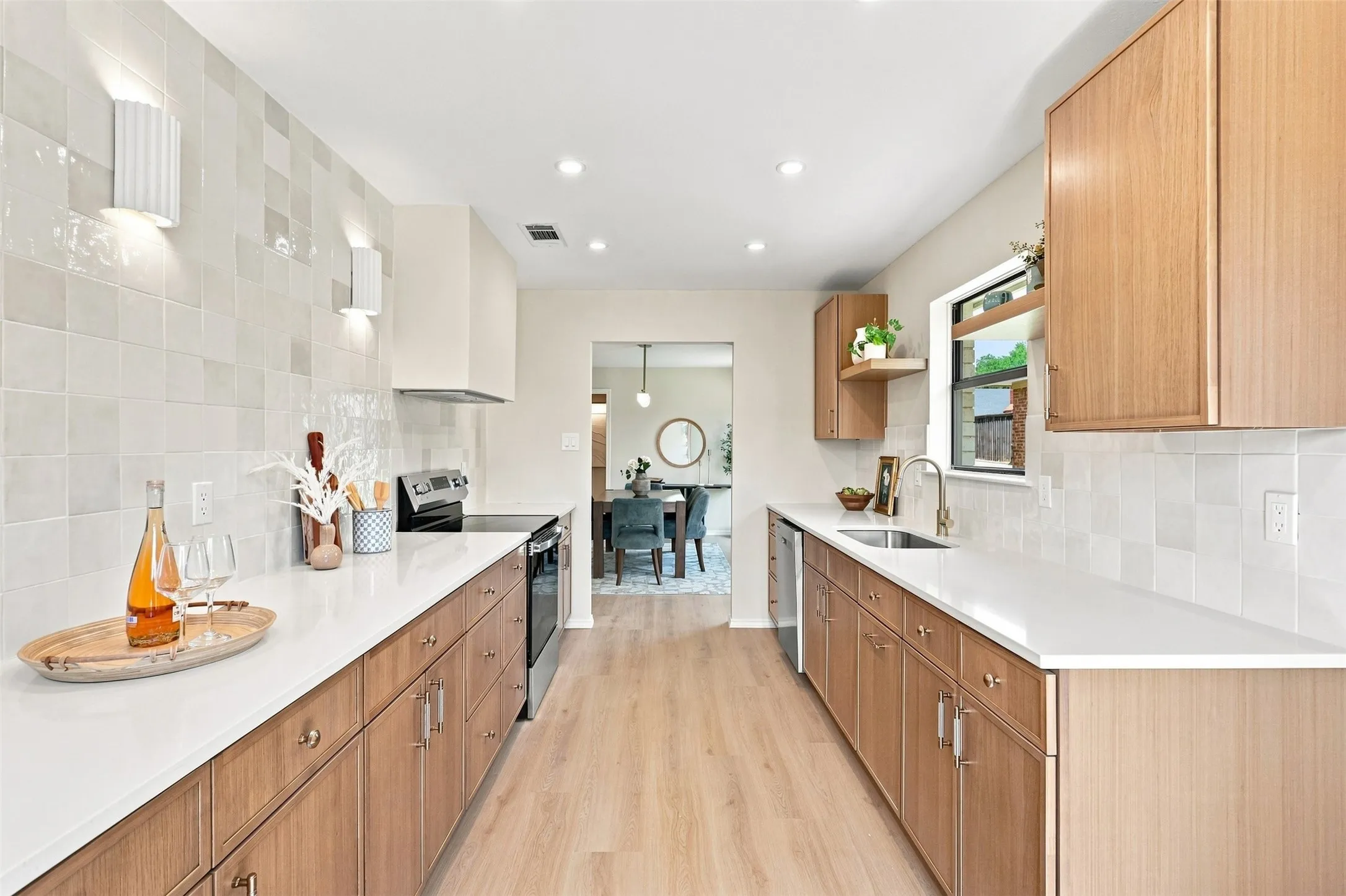 Galley kitchen featuring light wood-finish cabinetry, white countertops, a tiled backsplash, and recessed lighting