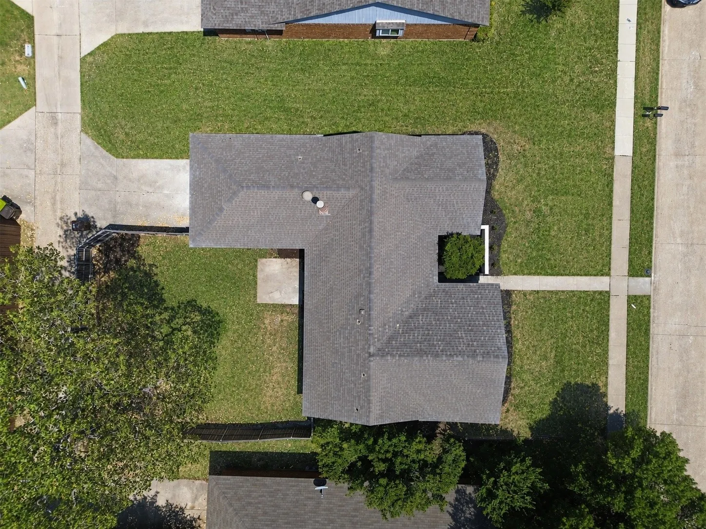 Asphalt shingle roof, concrete driveway, concrete sidewalk, front yard, and backyard