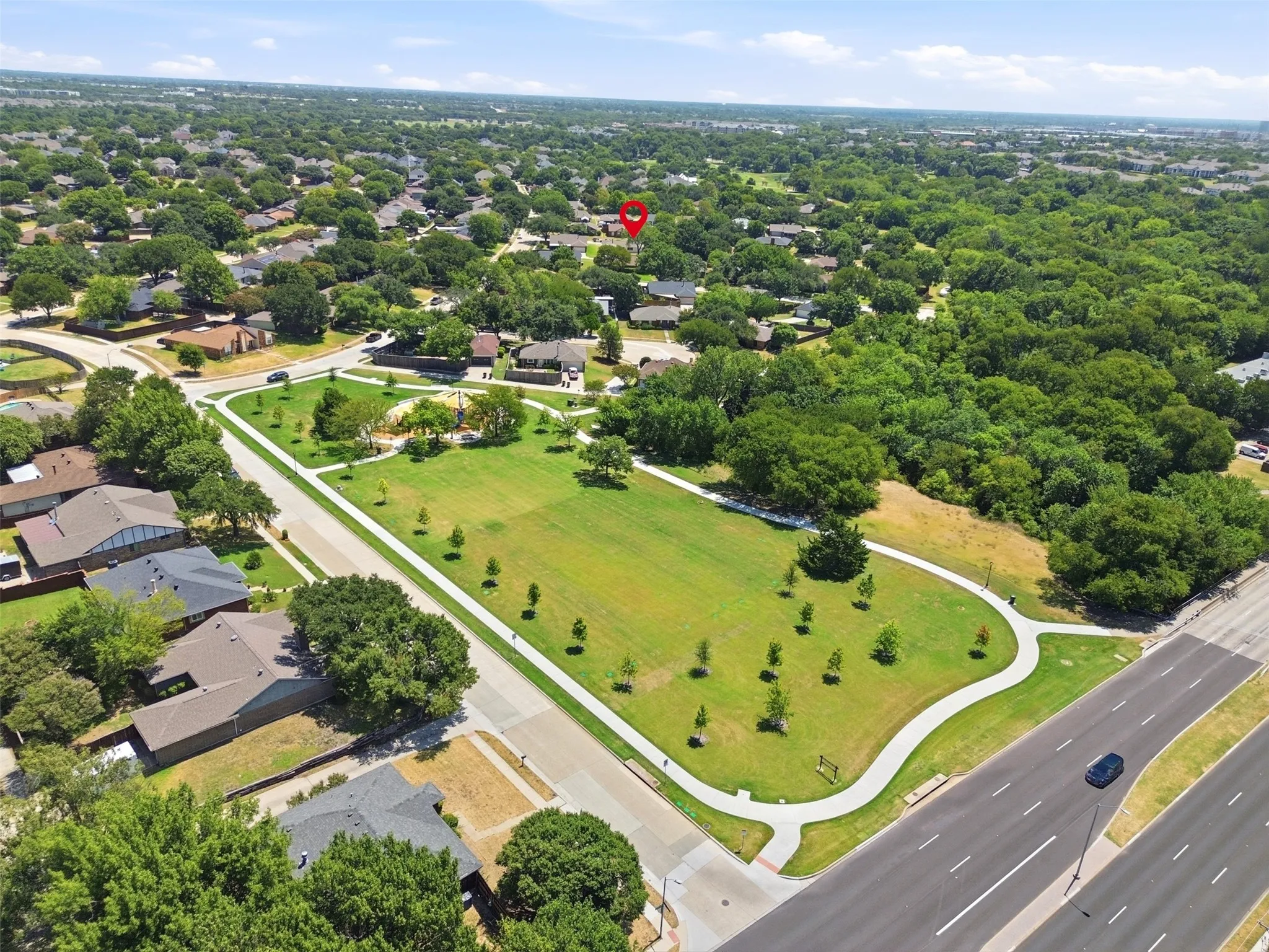Aerial perspective featuring a public park, mature trees, and residential properties