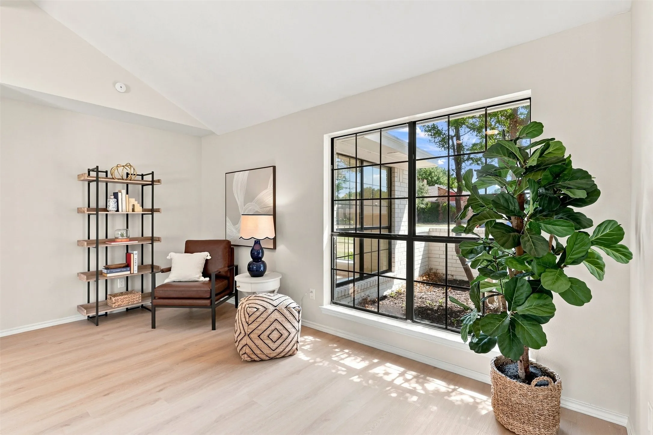 Vaulted ceiling, large grid-pattern window, wood-finish flooring, light-toned walls
