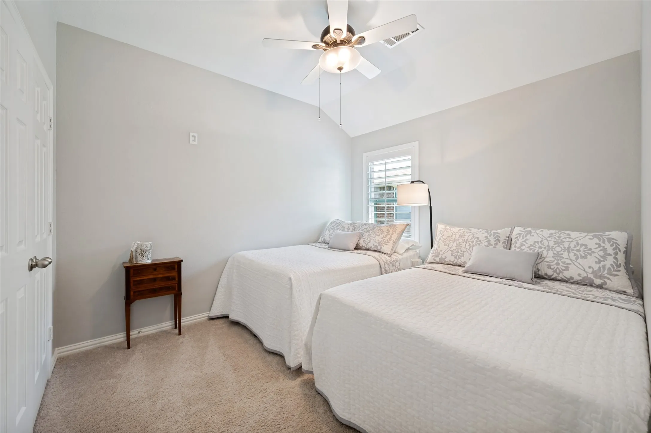 Raised ceiling with a ceiling fan, window with white plantation shutters, and light-colored wall-to-wall carpeting