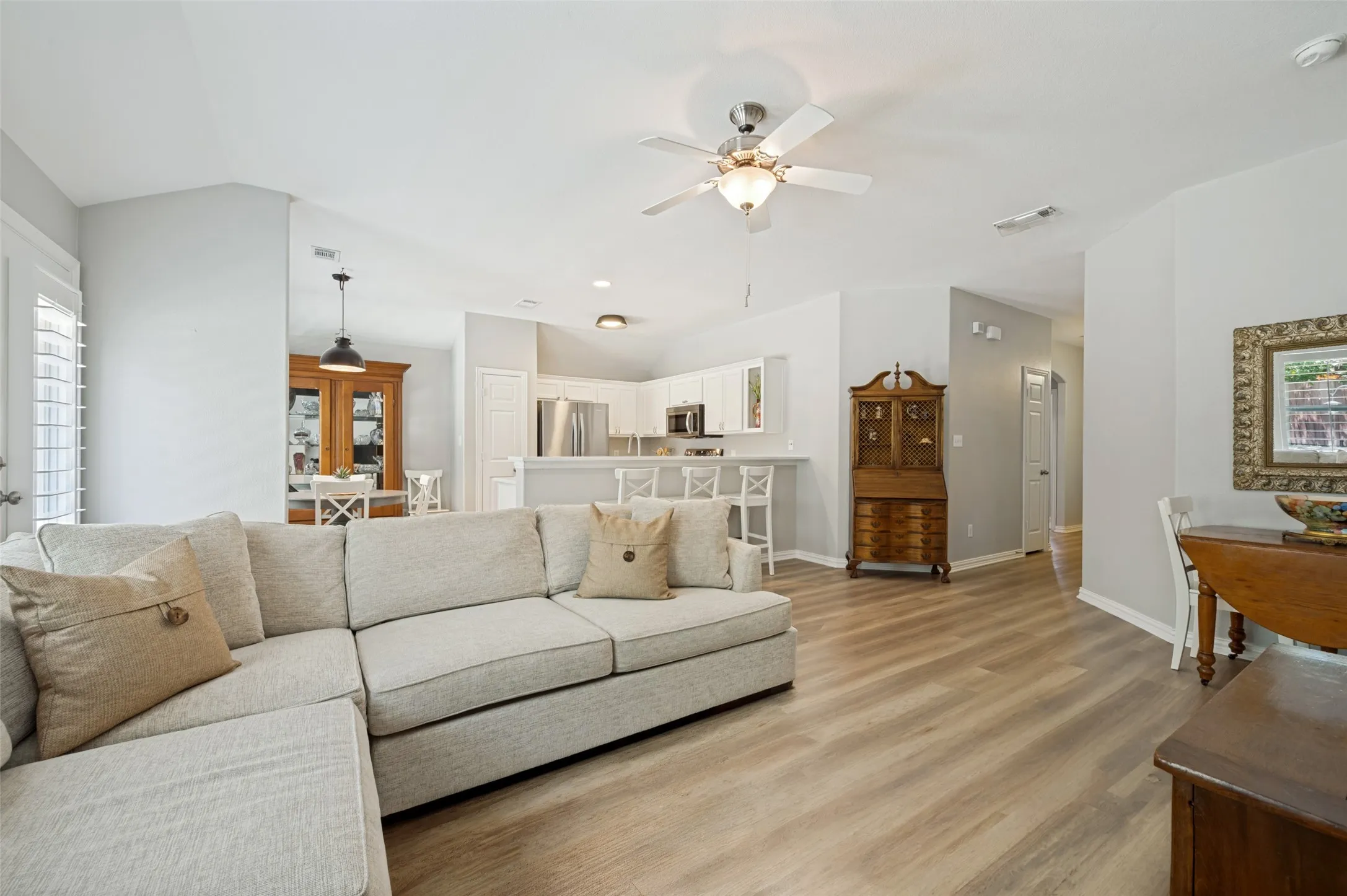 Open-concept living area featuring wood-finish flooring, vaulted ceilings, and a ceiling fan