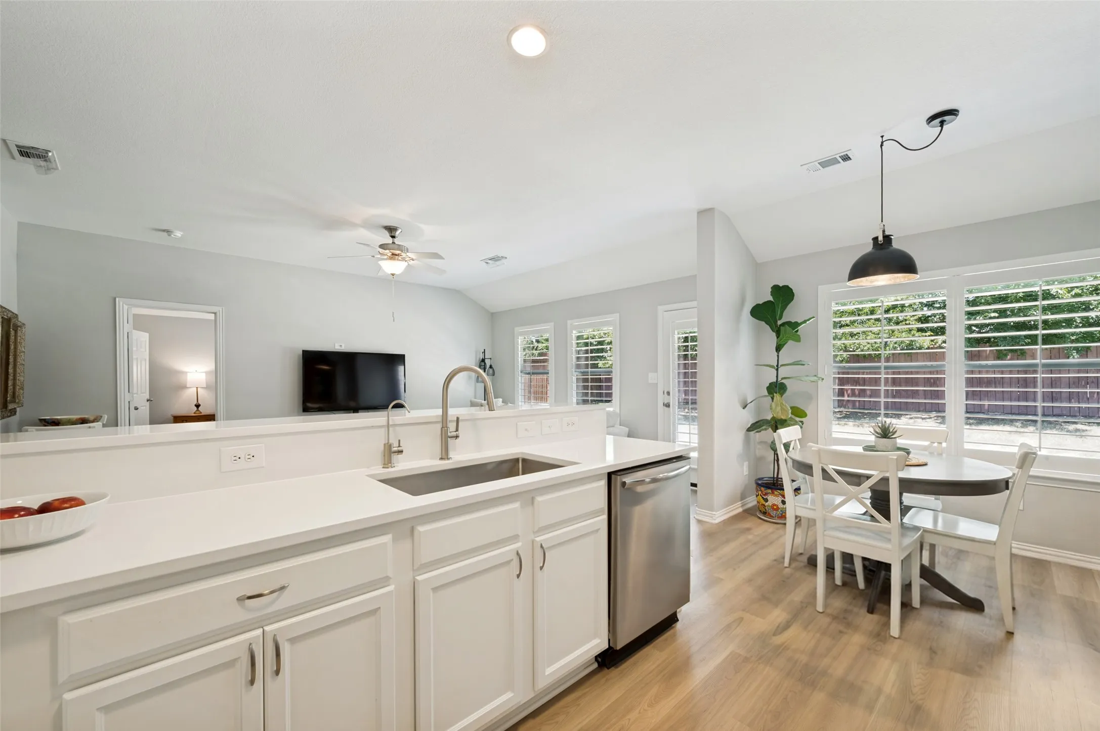 Kitchen featuring white cabinetry, light-toned countertops, a stainless steel sink, and wood-finish flooring