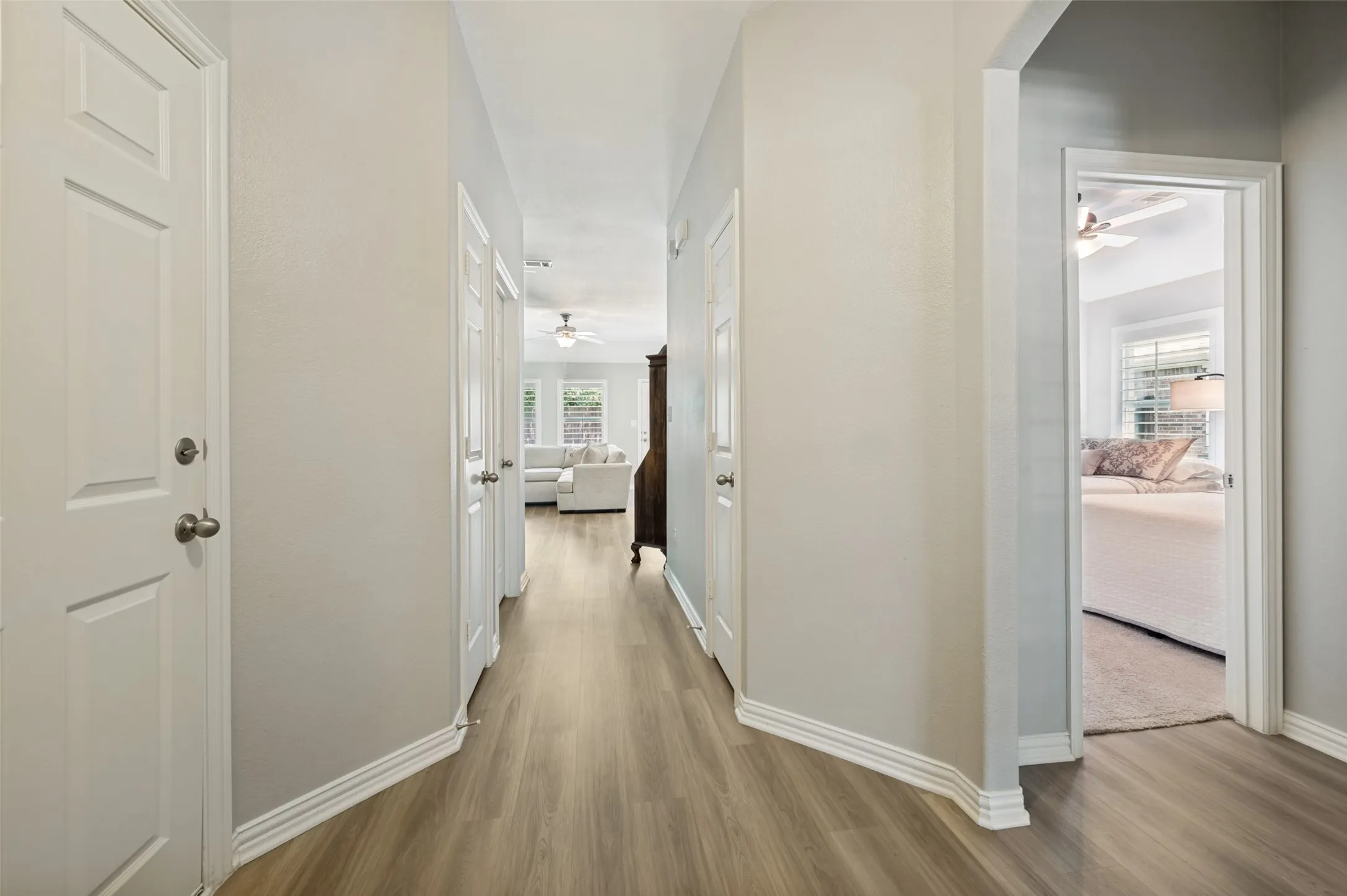 Hallway featuring wood-finish flooring, light-toned walls, and white trim
