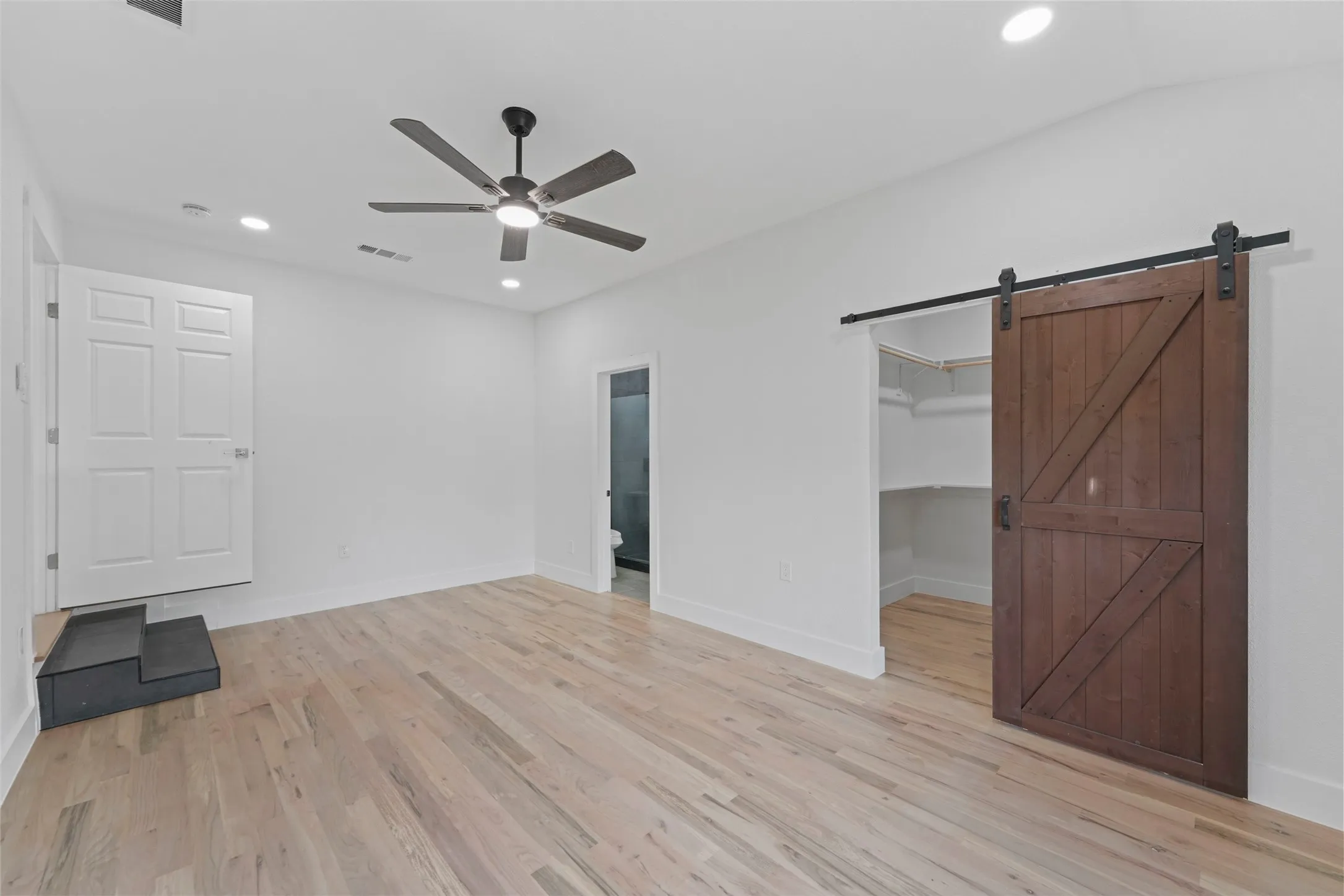 This spacious room features light hardwood floors, white walls, and recessed lighting, creating a bright and open atmosphere