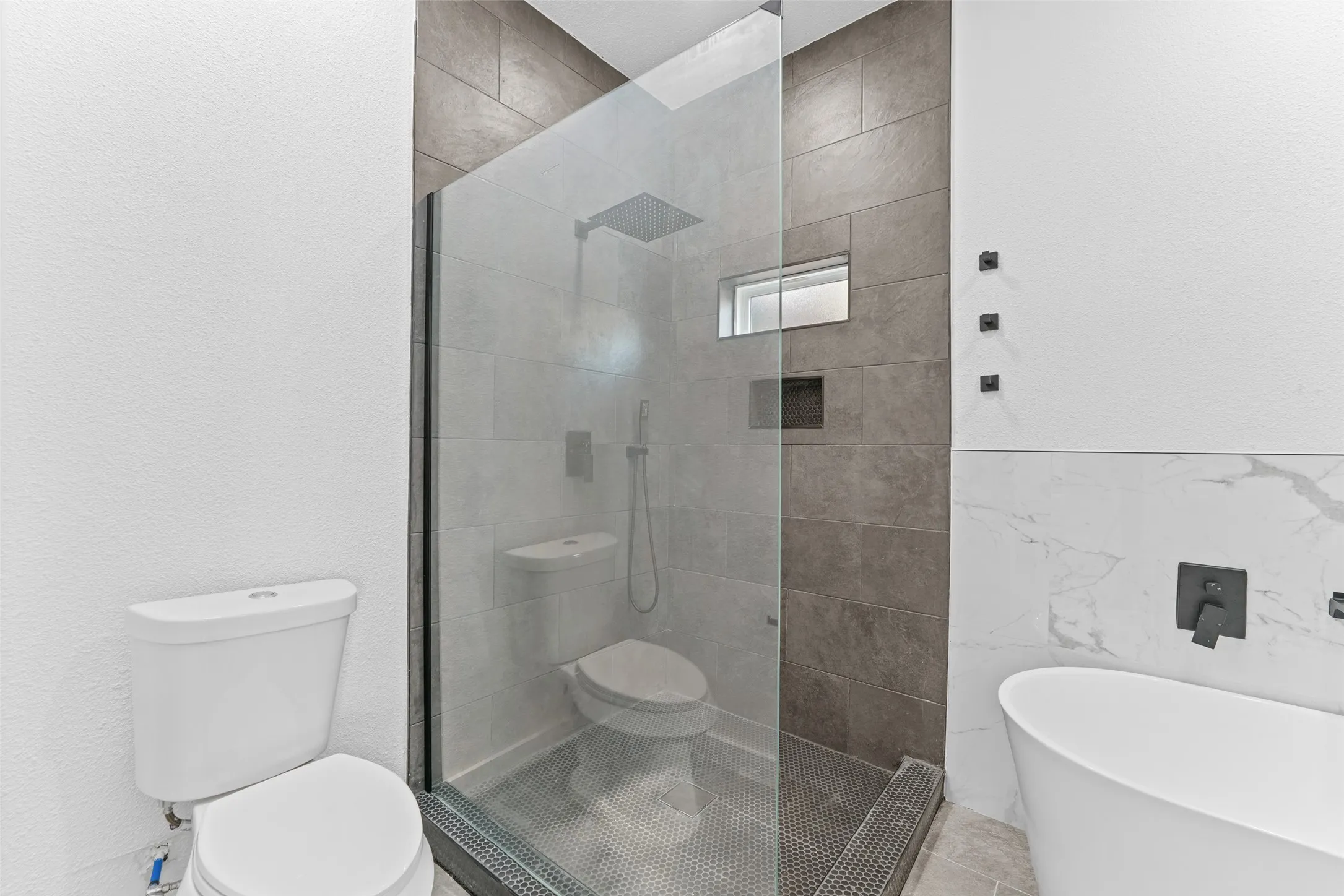 Modern bathroom featuring a freestanding soaking tub, a walk-in shower with a glass enclosure, and a toilet
