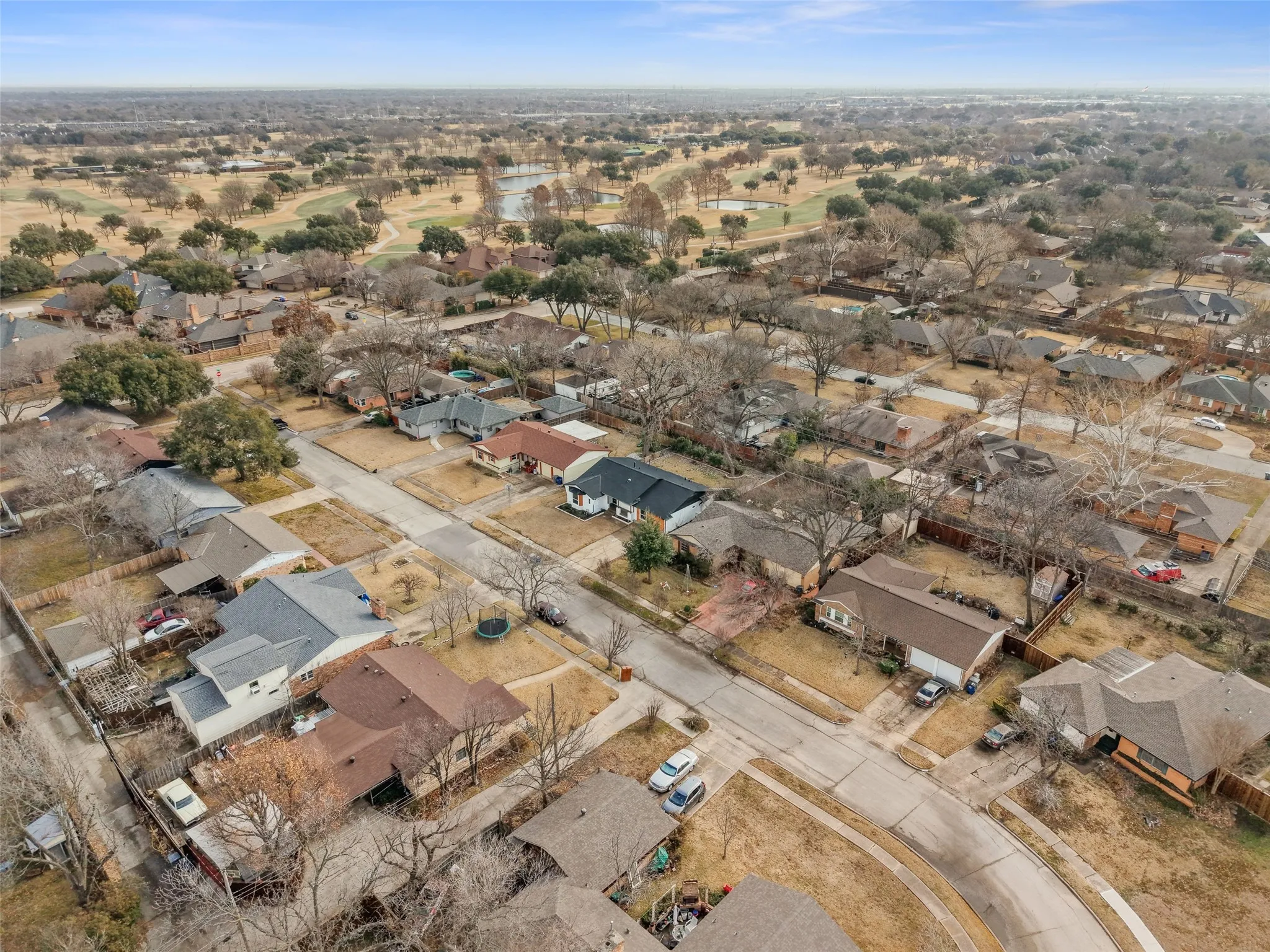 Aerial view of the neighborhood with a golf course and a pond visible in the background