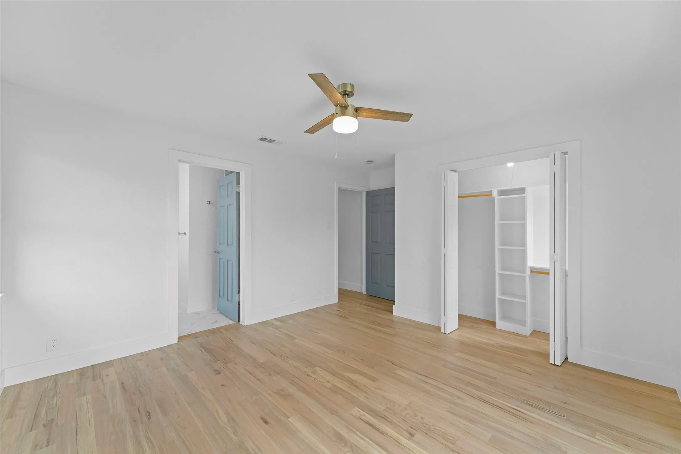 The room features light-toned hardwood flooring and a ceiling fan