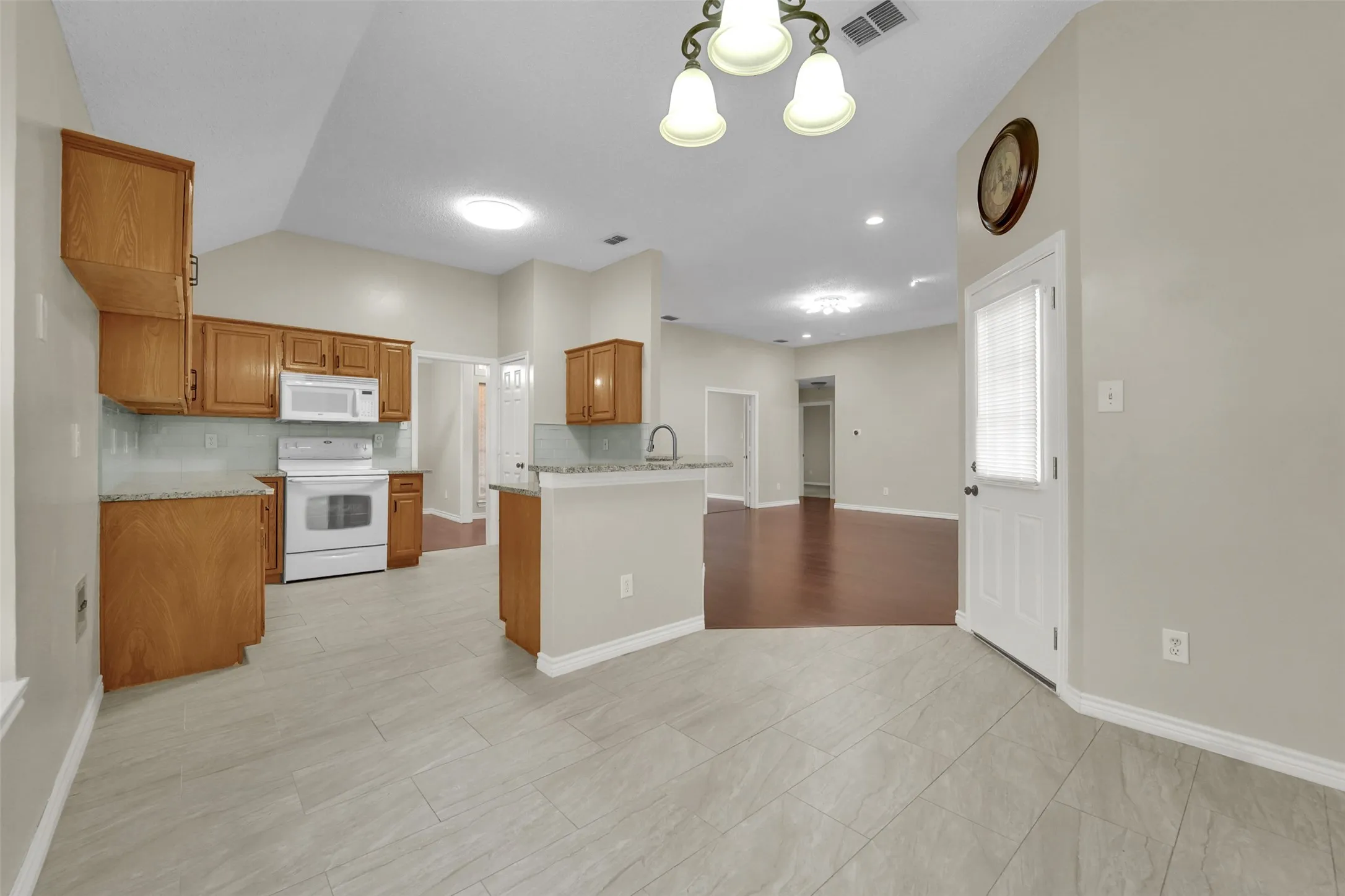 Kitchen featuring wood cabinetry, white appliances, and light-colored tile flooring