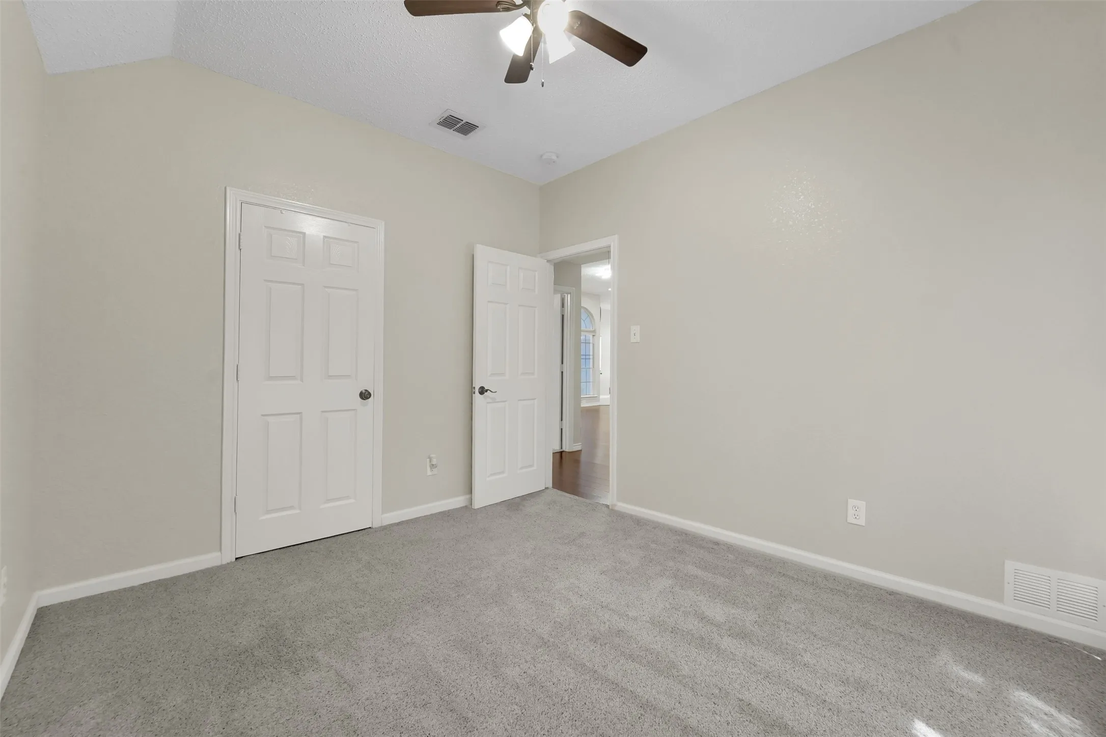 Vaulted ceiling featuring a ceiling fan with integrated lighting, neutral-toned walls, and grey carpeting
