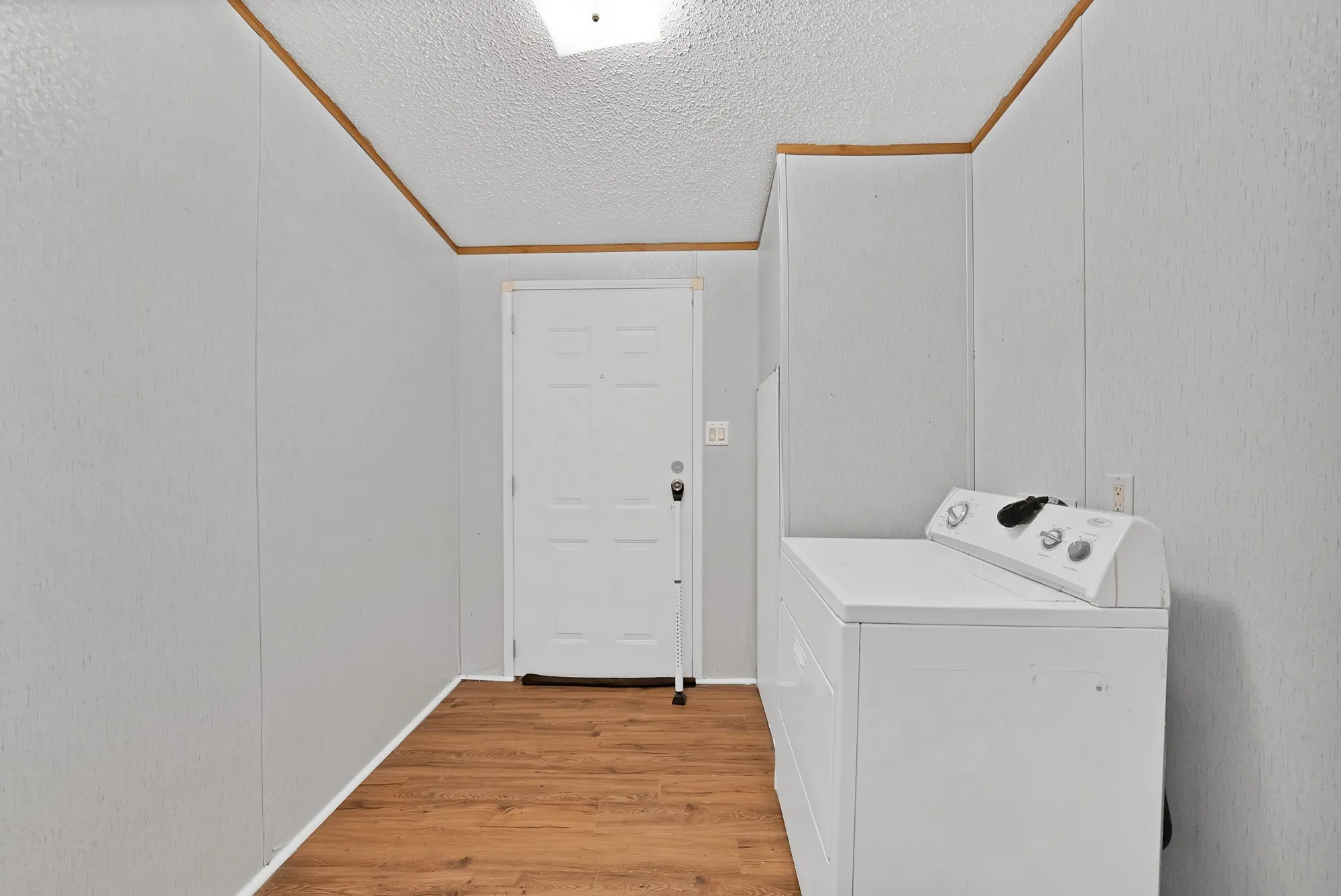 Wood-finish flooring, white paneling, and an overhead light fixture