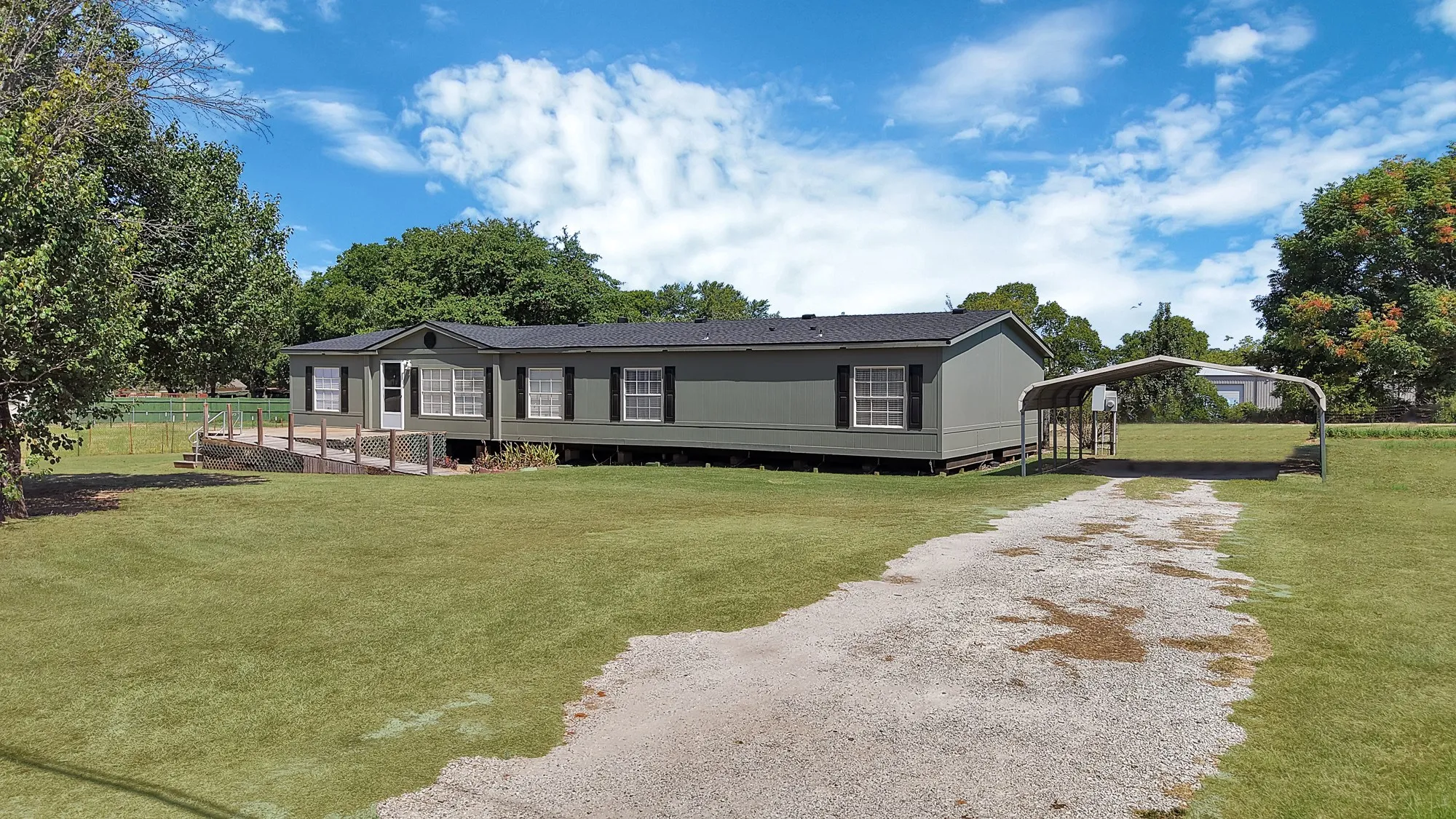 Exterior featuring gray siding, dark shutters, and a dark shingle roof