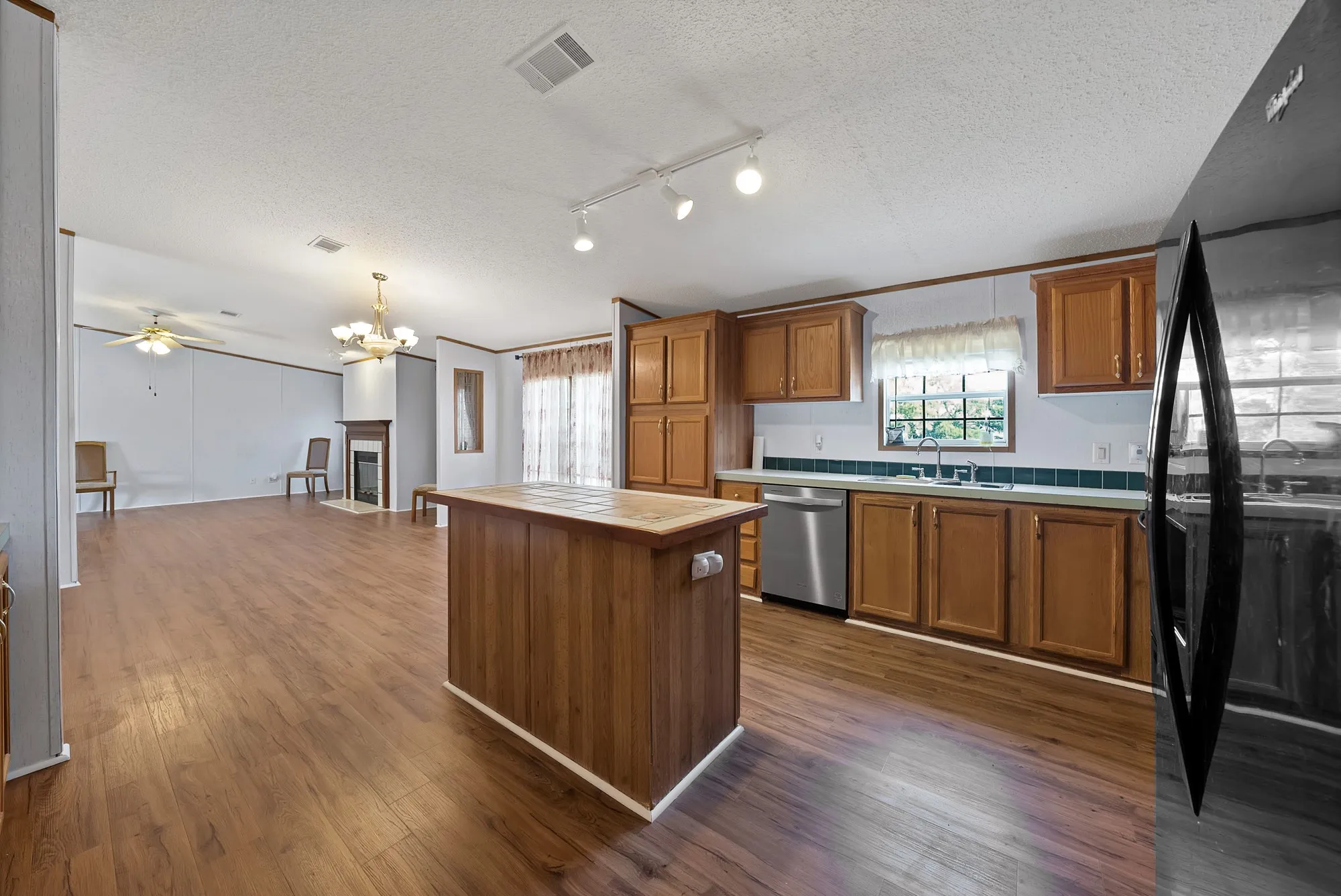 Open-concept living area with wood-finish flooring, a kitchen island, and a built-in fireplace