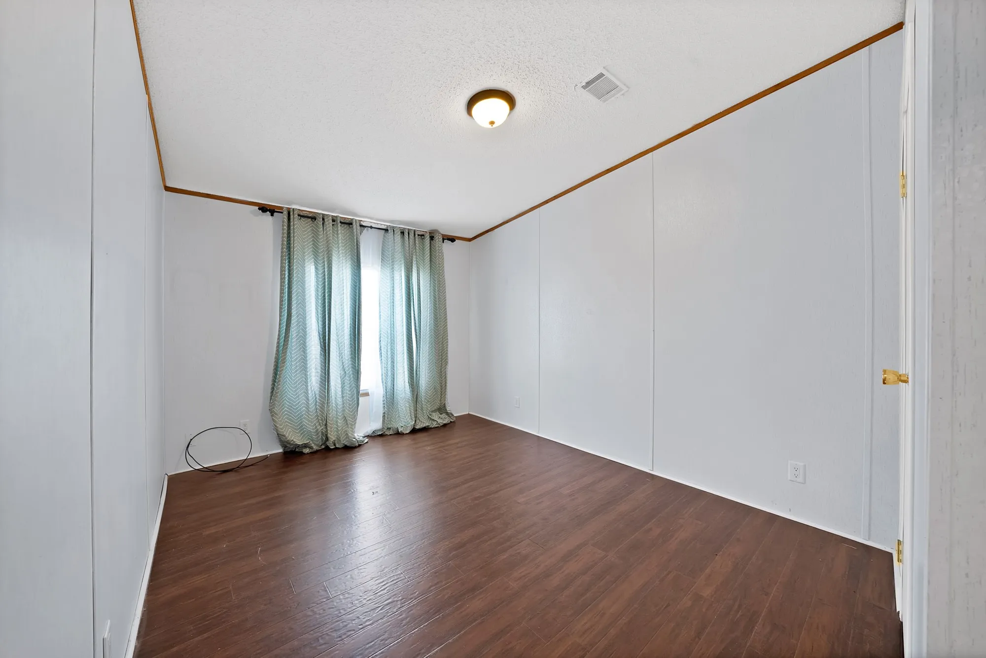 Wood-finish flooring, paneled walls, and a ceiling-mounted light fixture