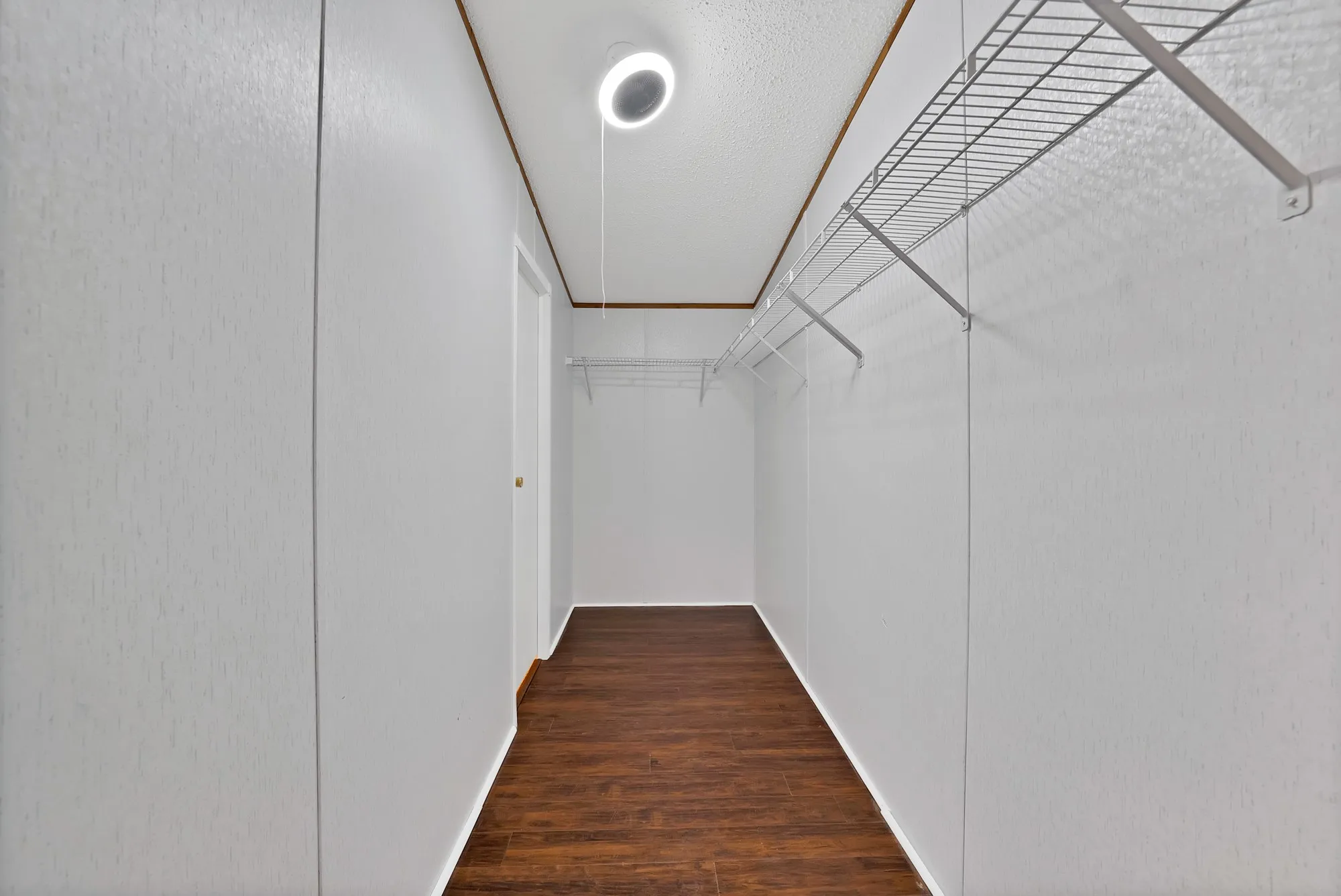 Spacious closet featuring wood-finish flooring, white wire shelving, and a recessed ceiling light