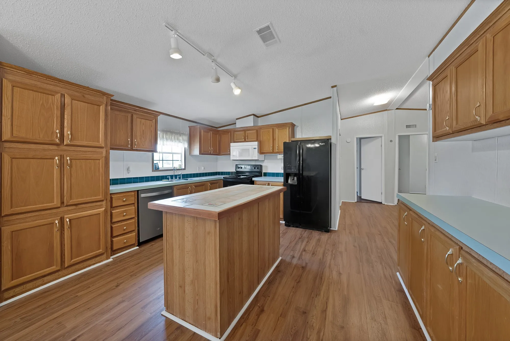 Kitchen featuring wood-finish flooring, ample cabinetry, a central island, and modern appliances