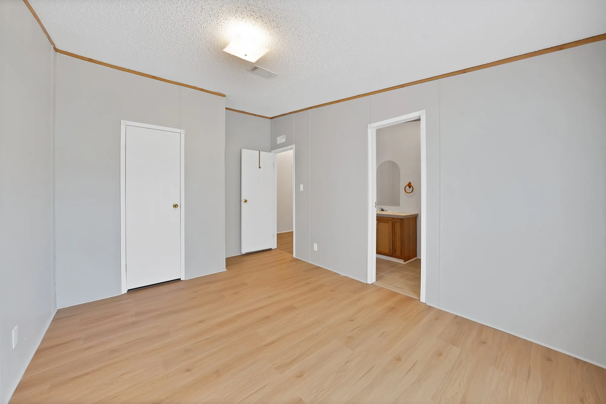 Wood-finish flooring throughout, light gray wall panels, and a flush mount ceiling light