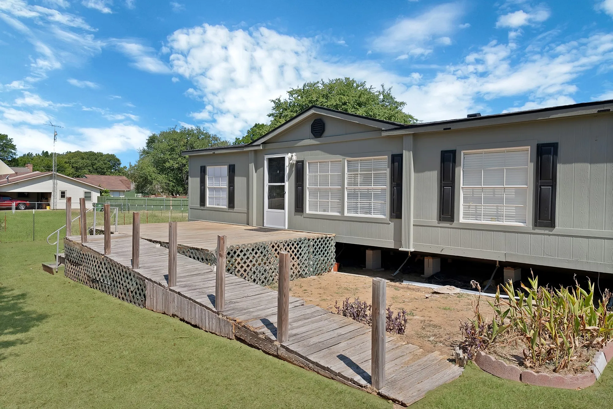 Exterior featuring a wood deck, wood ramp, and dark window shutters