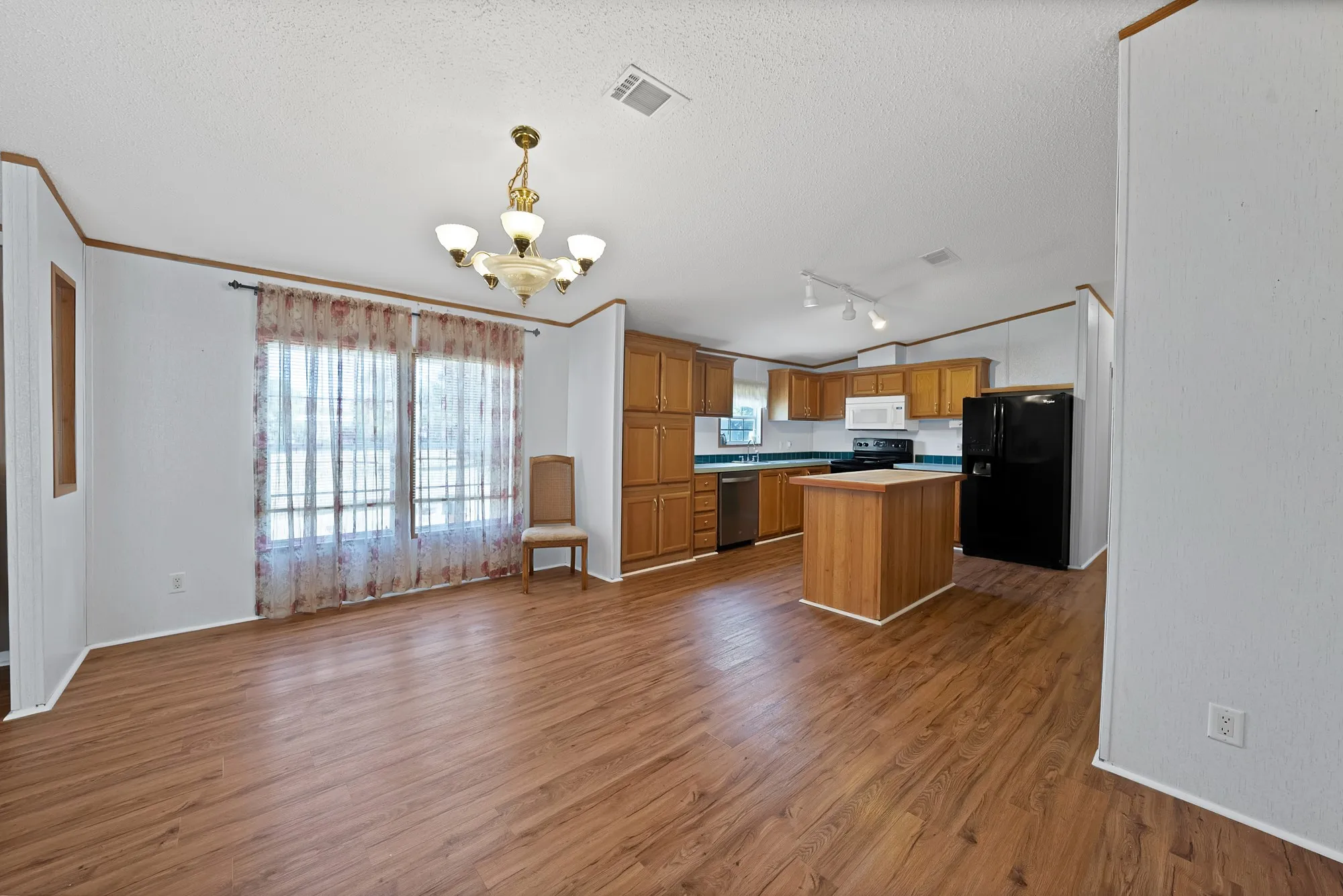 Wood-finish flooring throughout, kitchen with wood cabinetry, stainless steel dishwasher, and a center island with a wood countertop