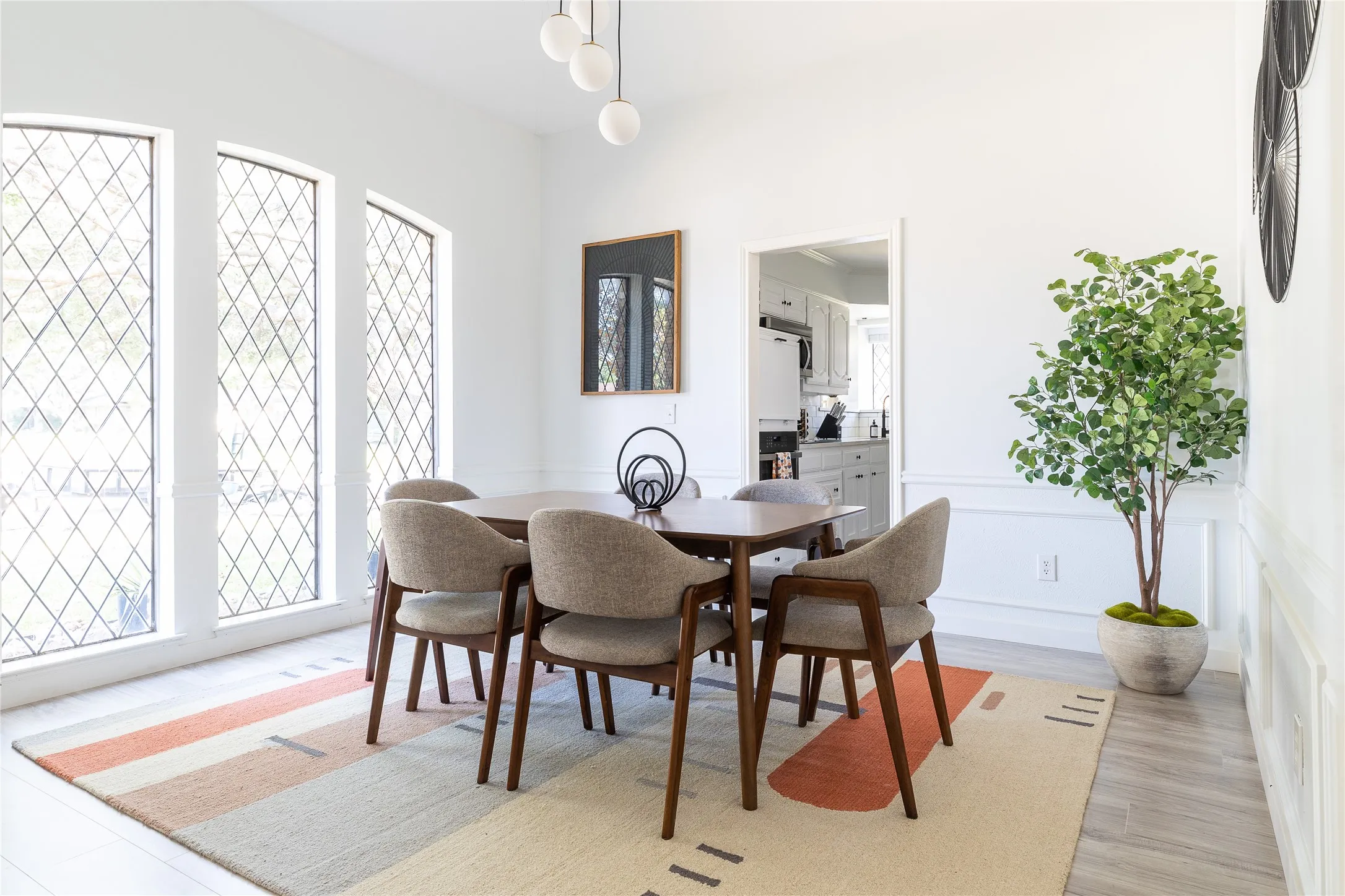 Three tall diamond-pane windows, decorative wall paneling, and an overhead spherical light fixture