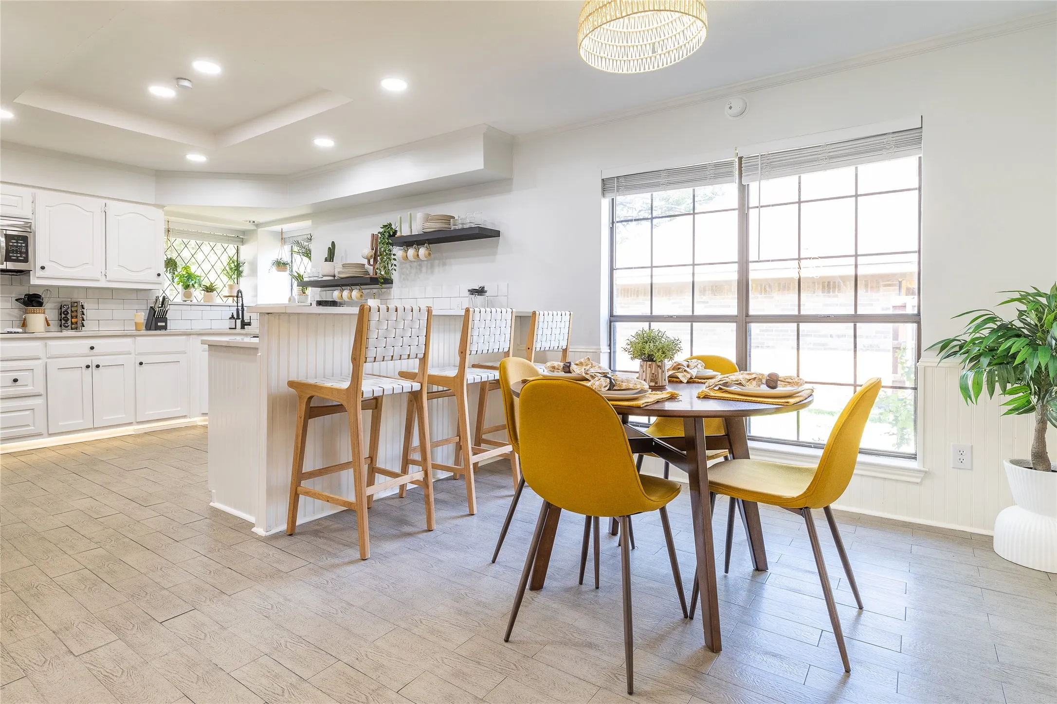 Kitchen area with white cabinetry, a built-in island with seating, open shelving, and wood-finish flooring