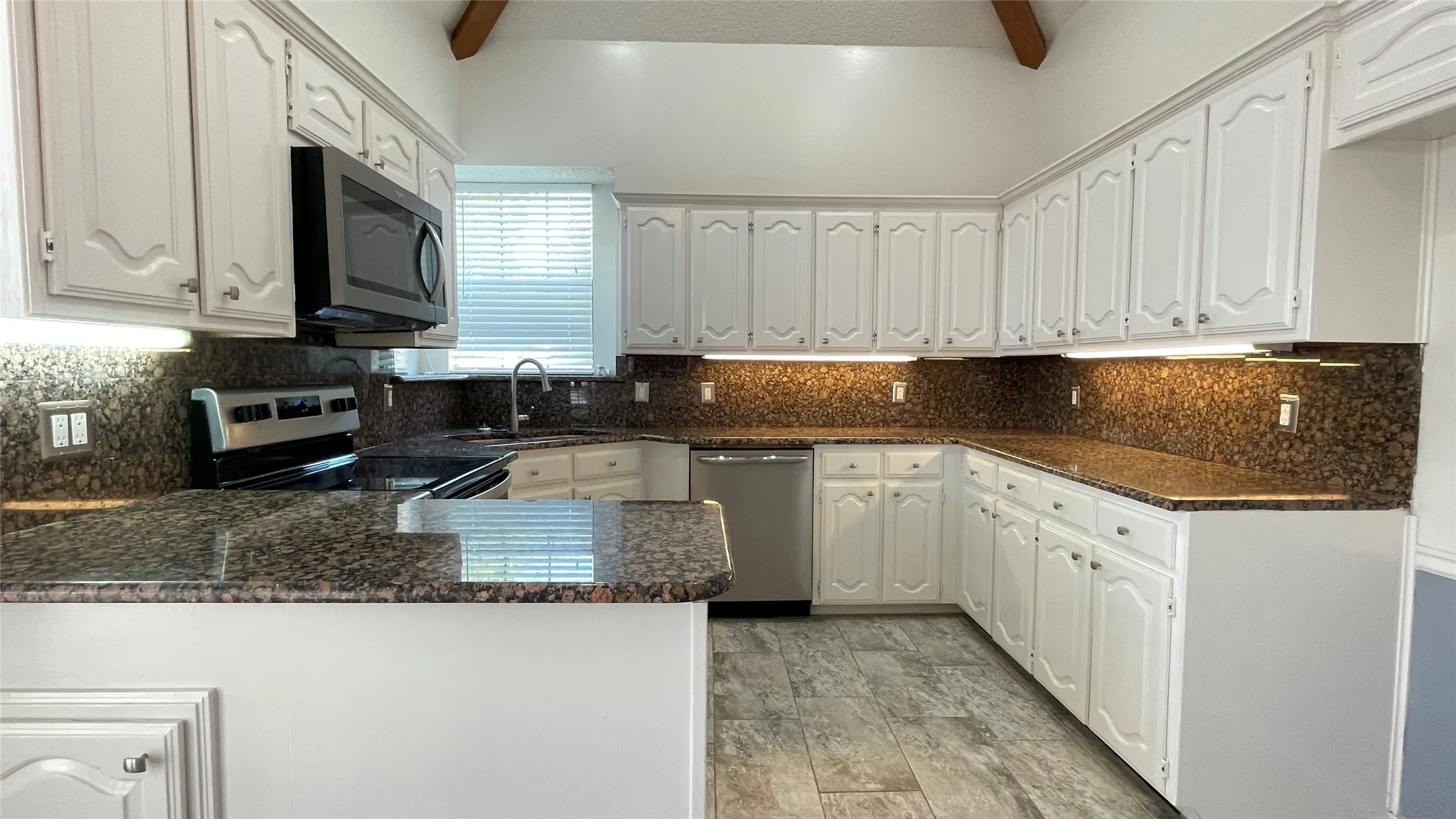 Rectangular tile floor. Granite counter tops. lights under cabinets. Vaulted ceiling.