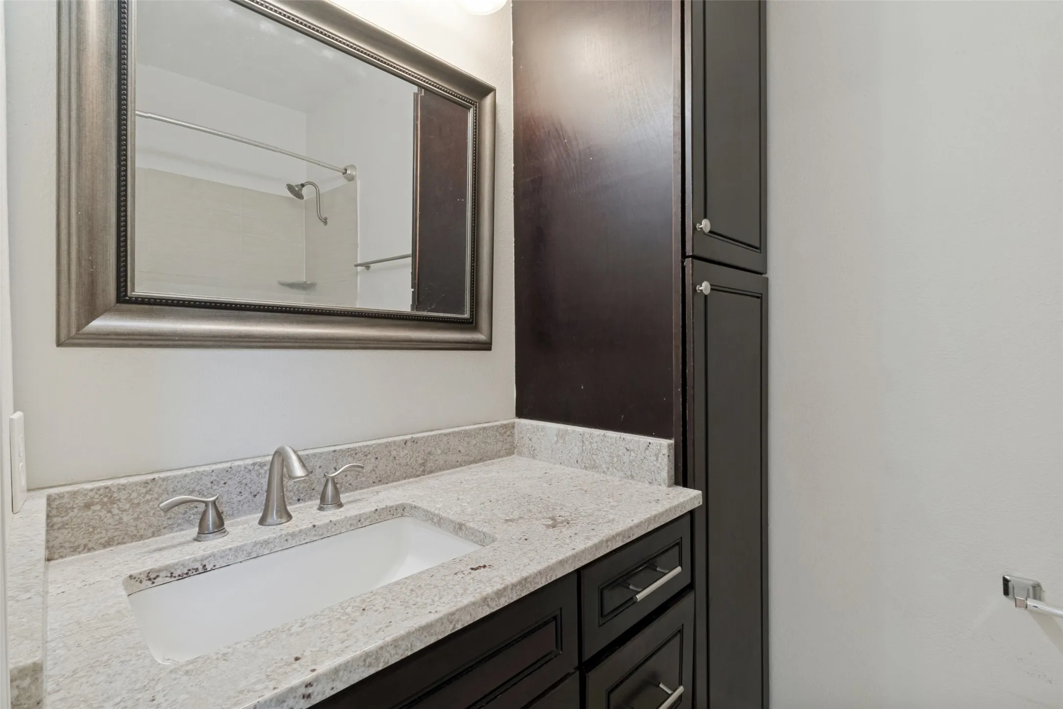 Vanity with a granite-style countertop, undermount sink, and brushed nickel fixtures