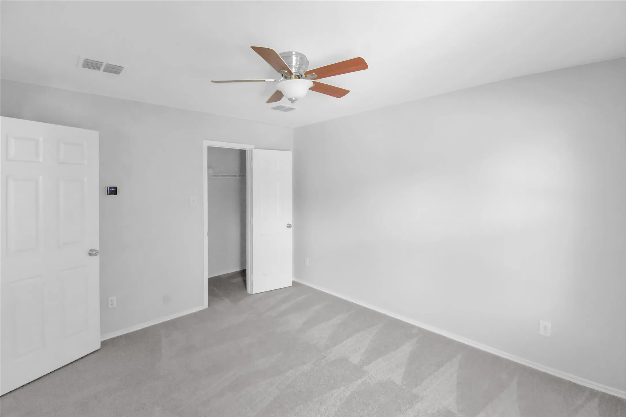 Plush carpeting, neutral wall finishes, ceiling fan with integrated lighting, and multiple panel doors