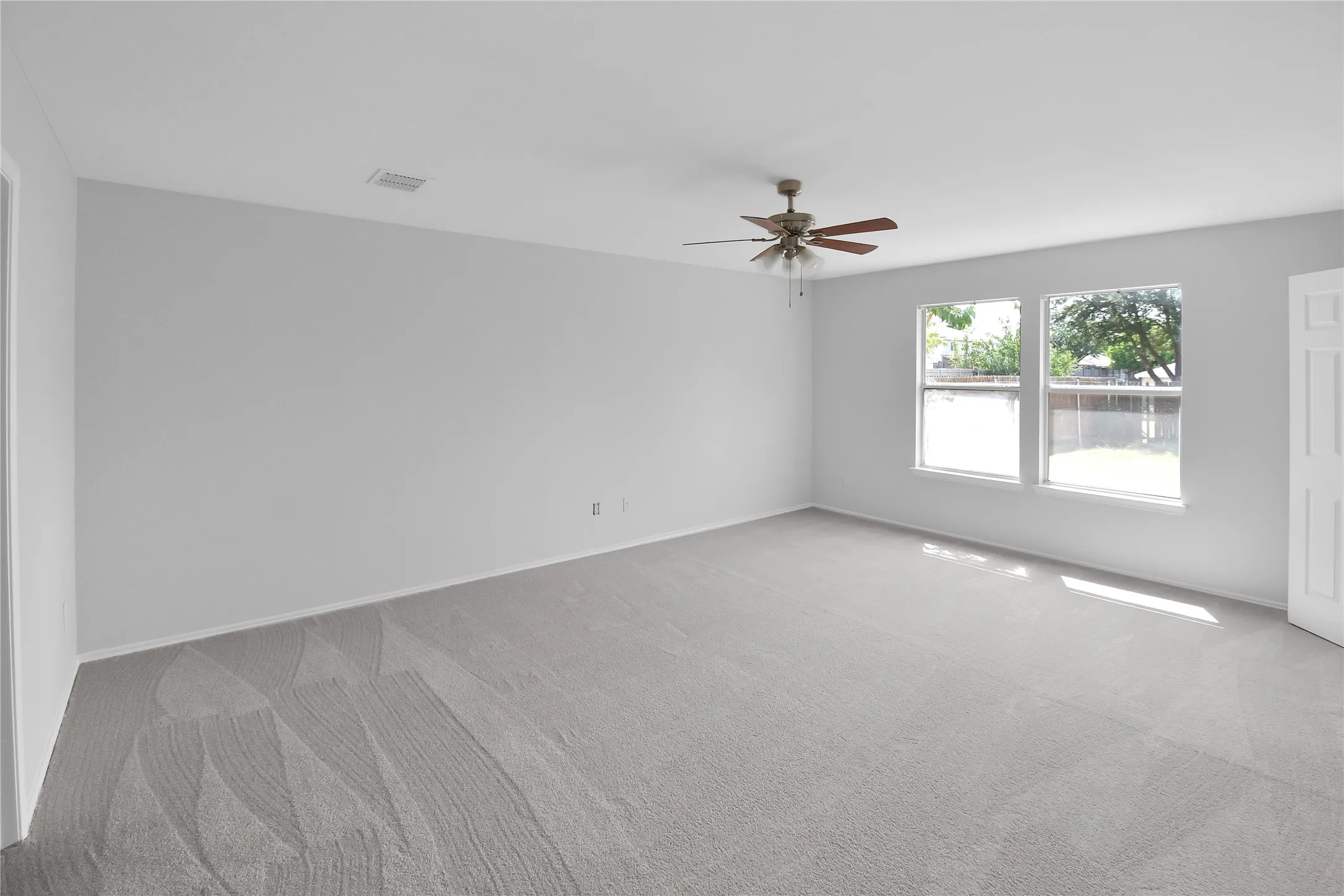 Spacious room flooded with natural light through dual glass doors and windows