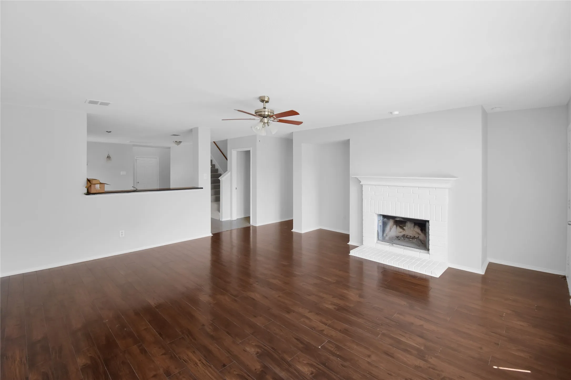 Spacious open-concept living area featuring rich wood-finish flooring throughout, recessed lighting, and a ceiling fan
