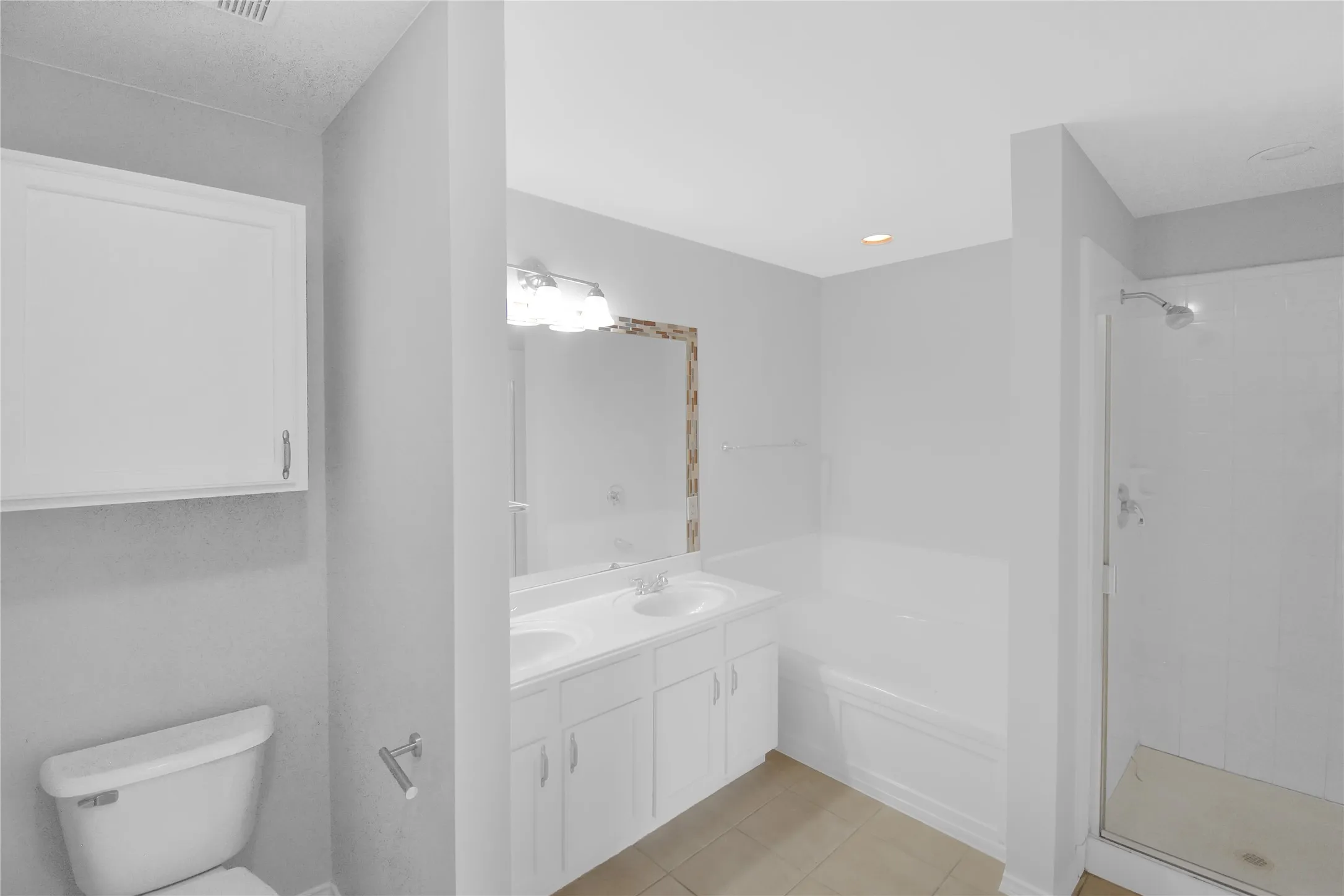 Modern primary bathroom featuring a white dual-sink vanity with ample storage, quartz countertop, and chrome fixtures