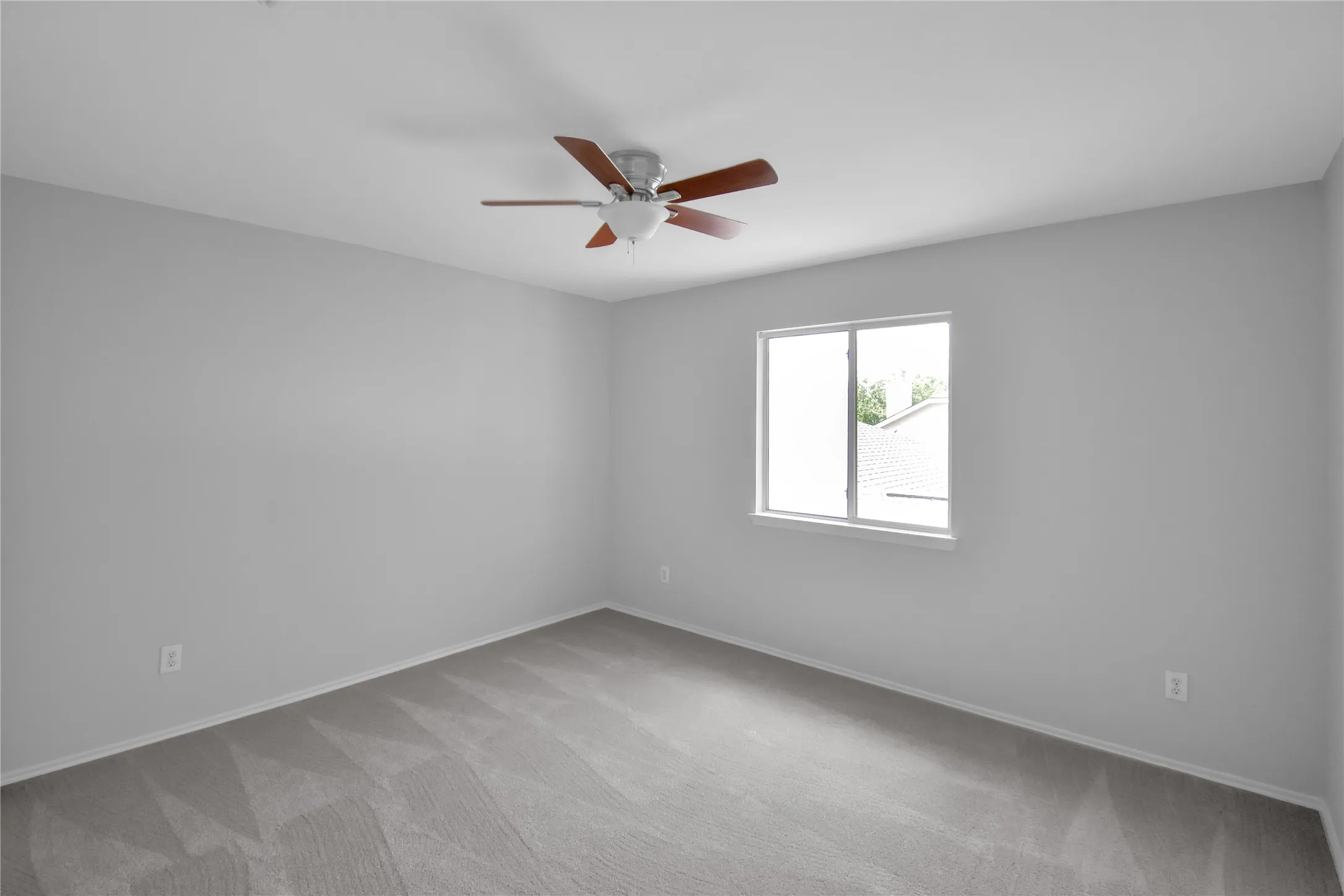 Carpeted room featuring a ceiling fan with light fixture and a window
