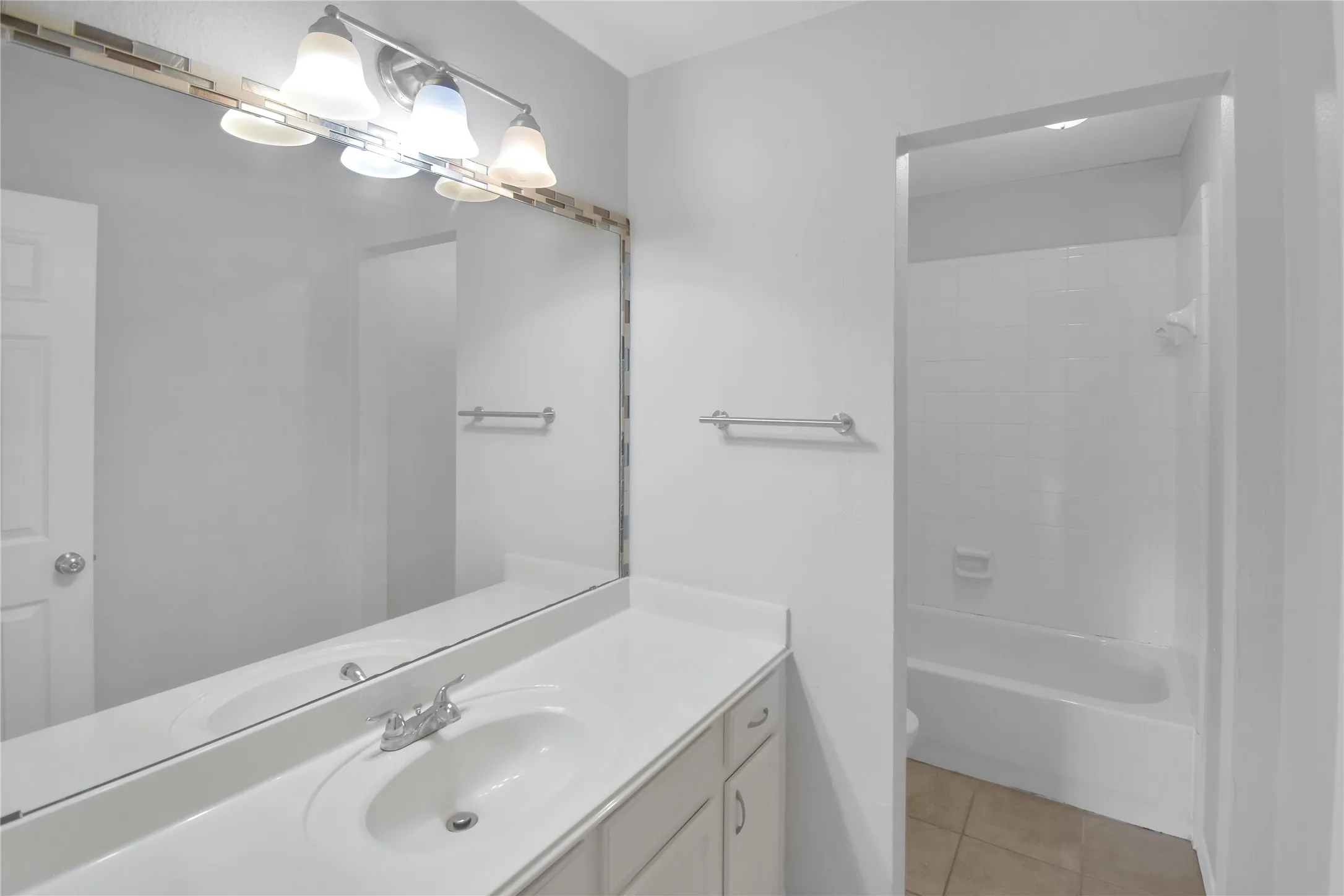 Vanity with an integrated sink, polished chrome faucet, and a large wall-mounted mirror