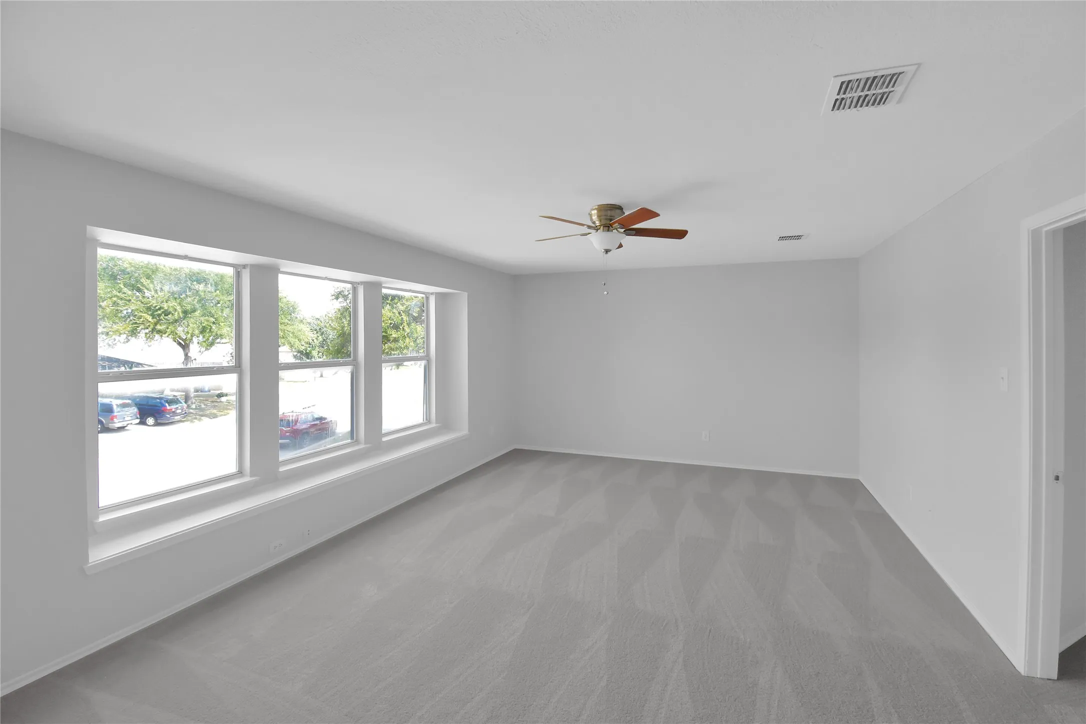 Recessed ceiling light, ceiling fan with wood-finish blades, light-toned carpeting, and a white door frame