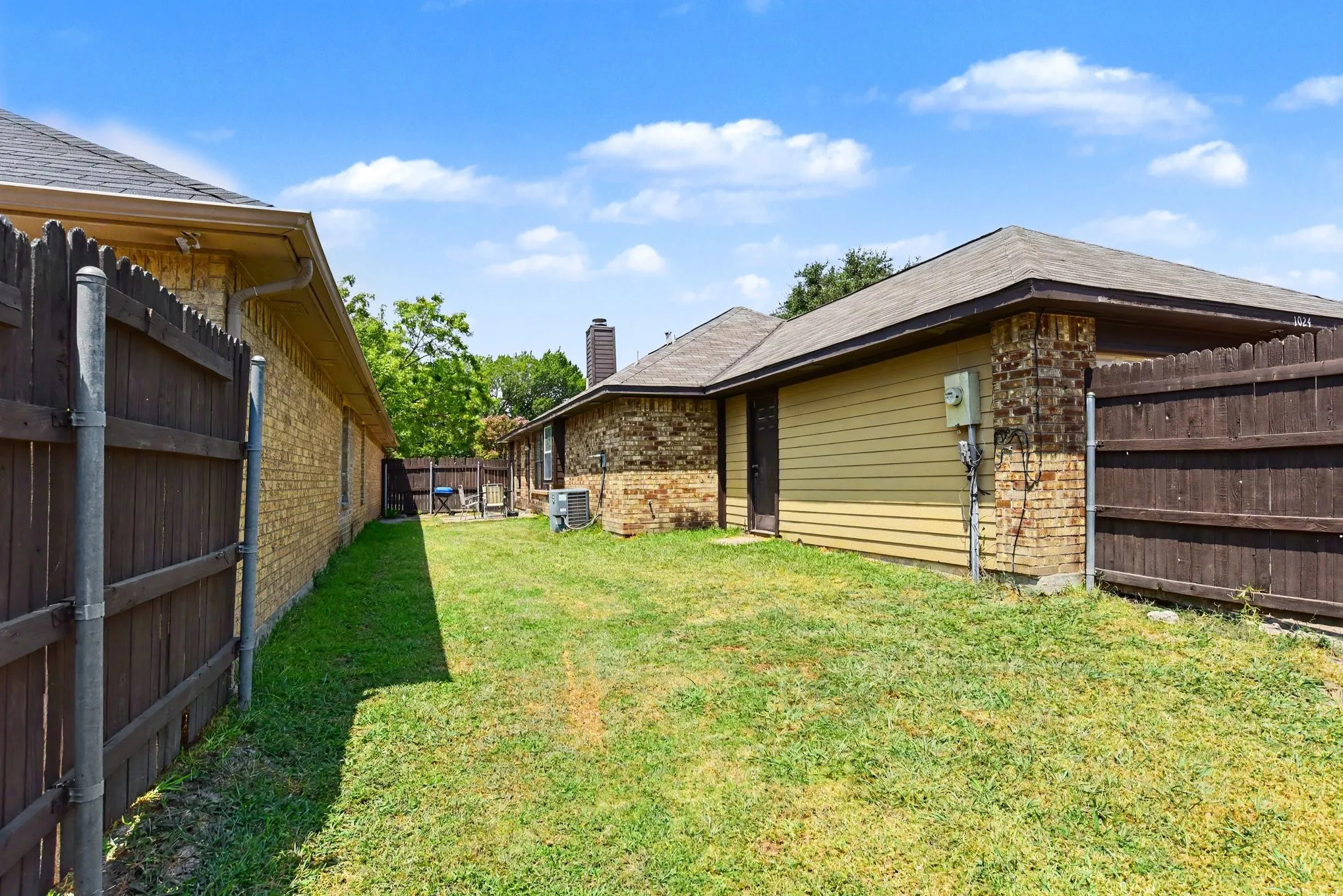 Fenced backyard lawn bounded by full wooden privacy fencing.