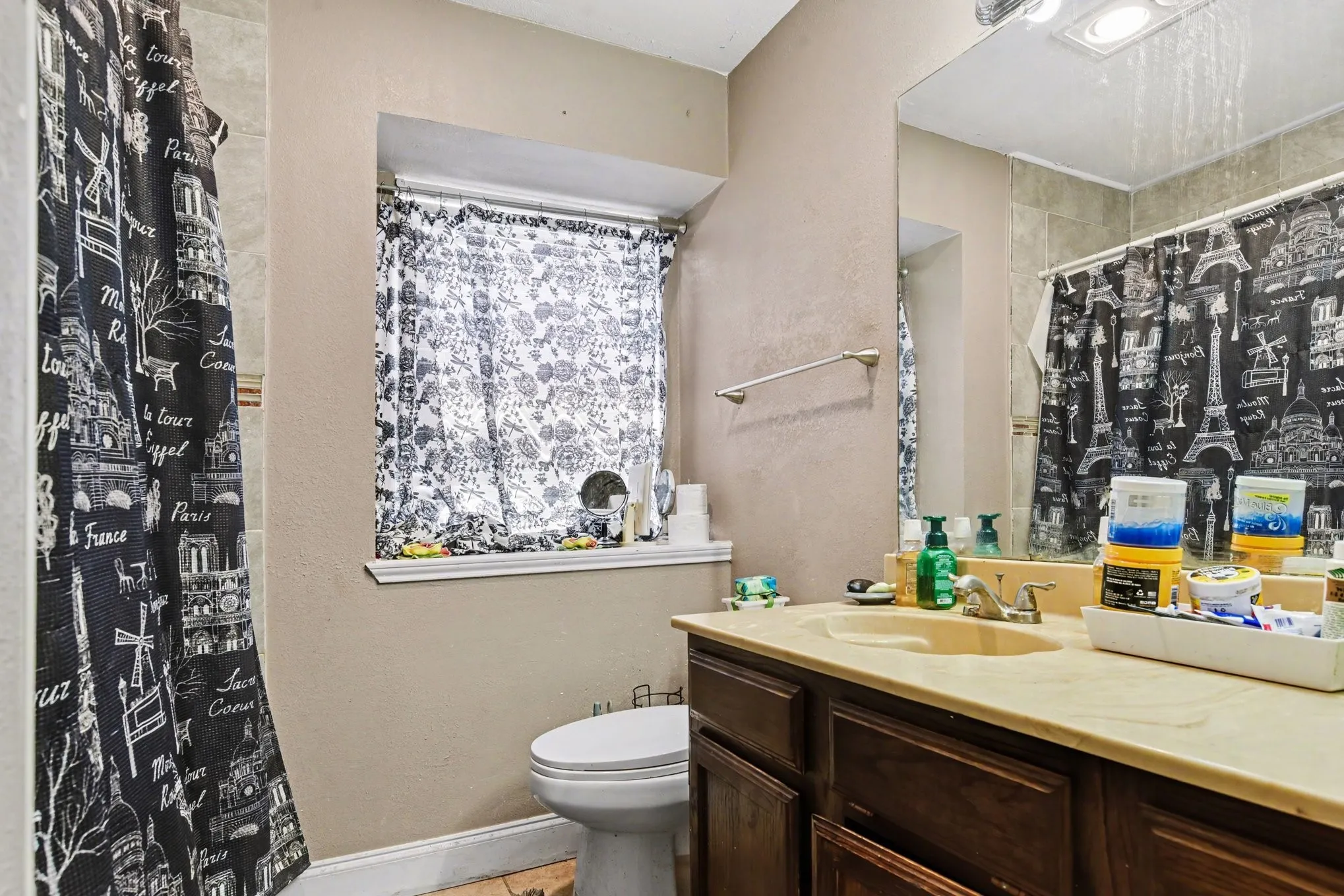Bathroom view highlighting vanity sink, toilet, privacy window, and tub/shower combination.