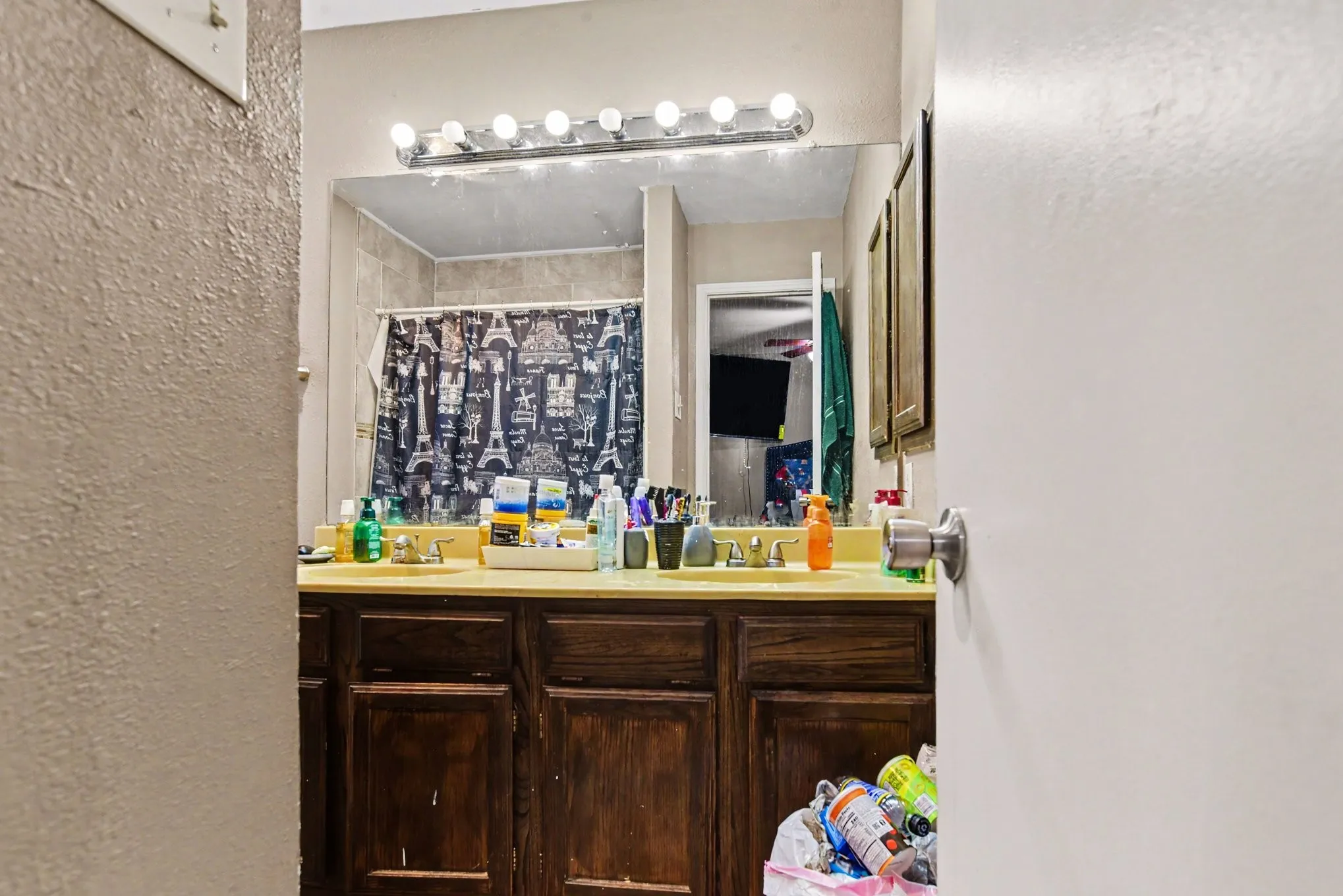 Full bathroom with dark wood vanity cabinet, bright multi-bulb light fixture, and large mirror.